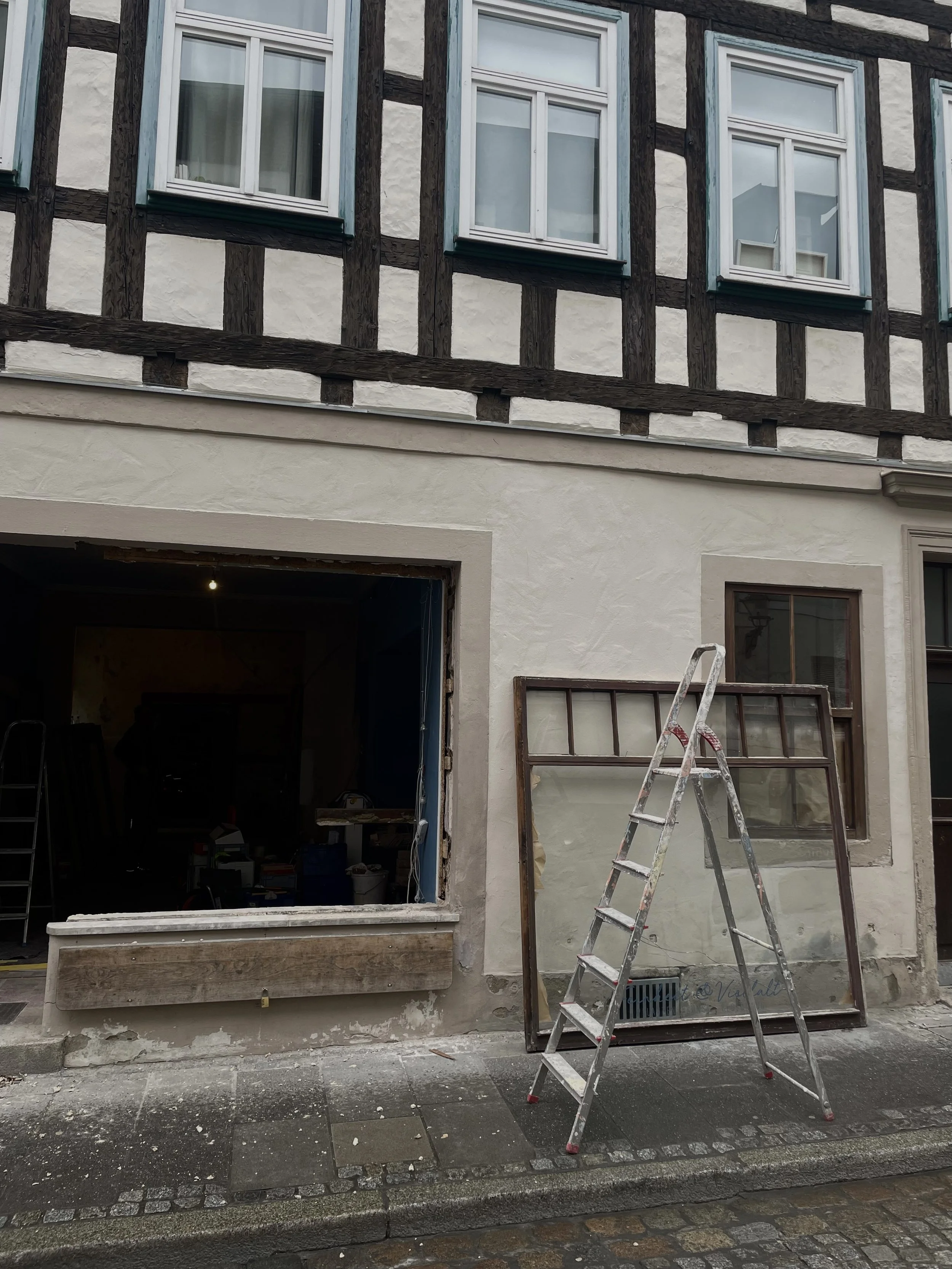 Der Eingang eines Hauses während Renovierungsarbeiten mit einer Leiter und ungeputzter Fassade.