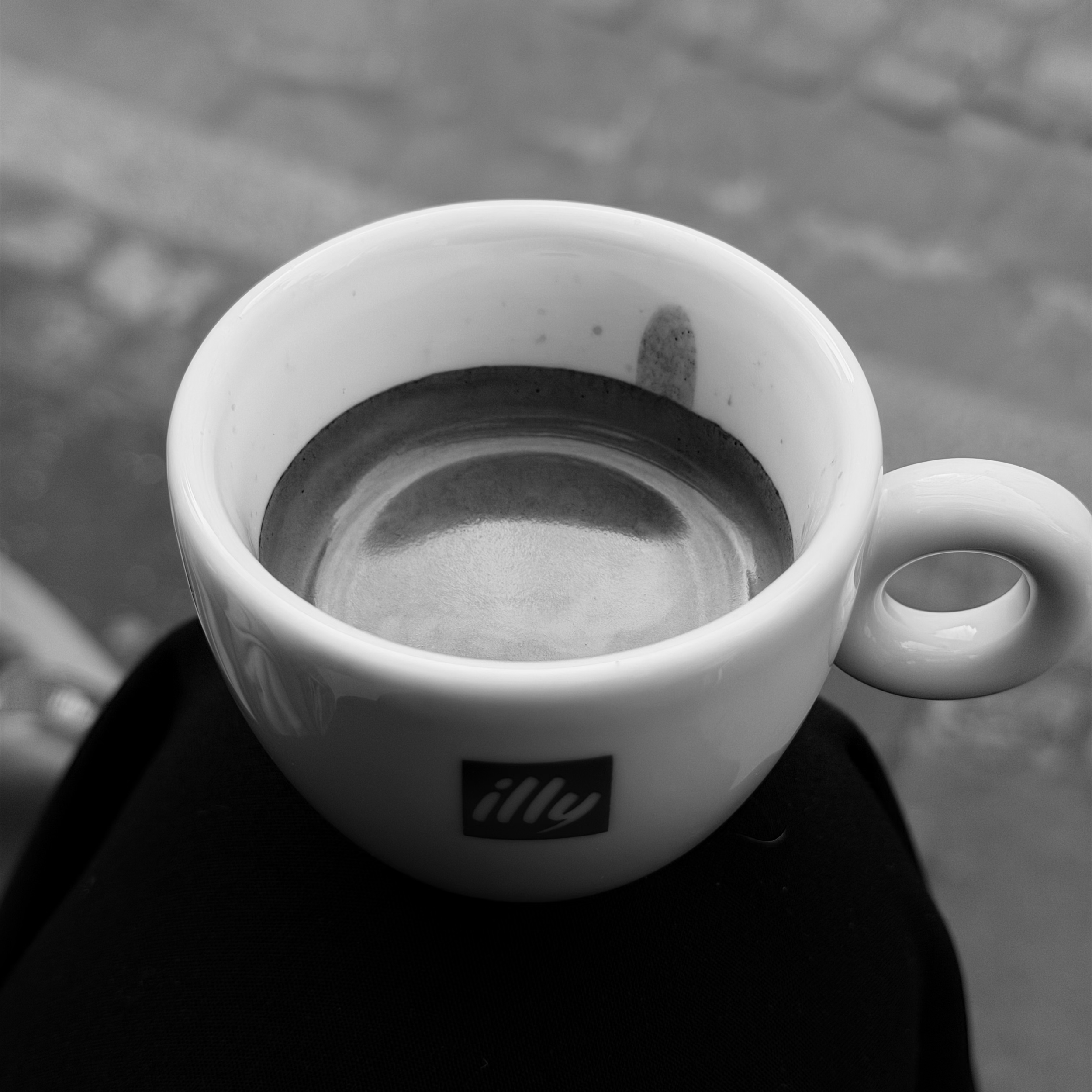 Schwarze und weiße Kaffeetasse auf einem Tisch, Nahaufnahme, schwarz-weiß.