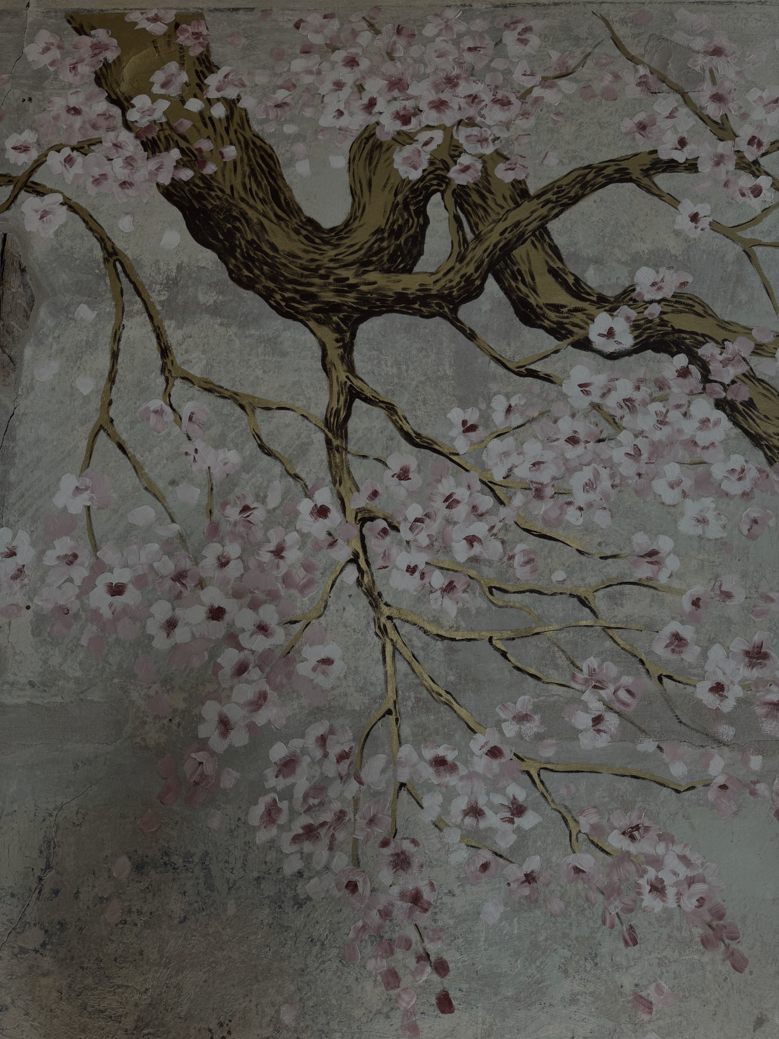 Eine Wandmalerei eines blühenden Kirschbaums mit rosa Blüten auf grauem Hintergrund.