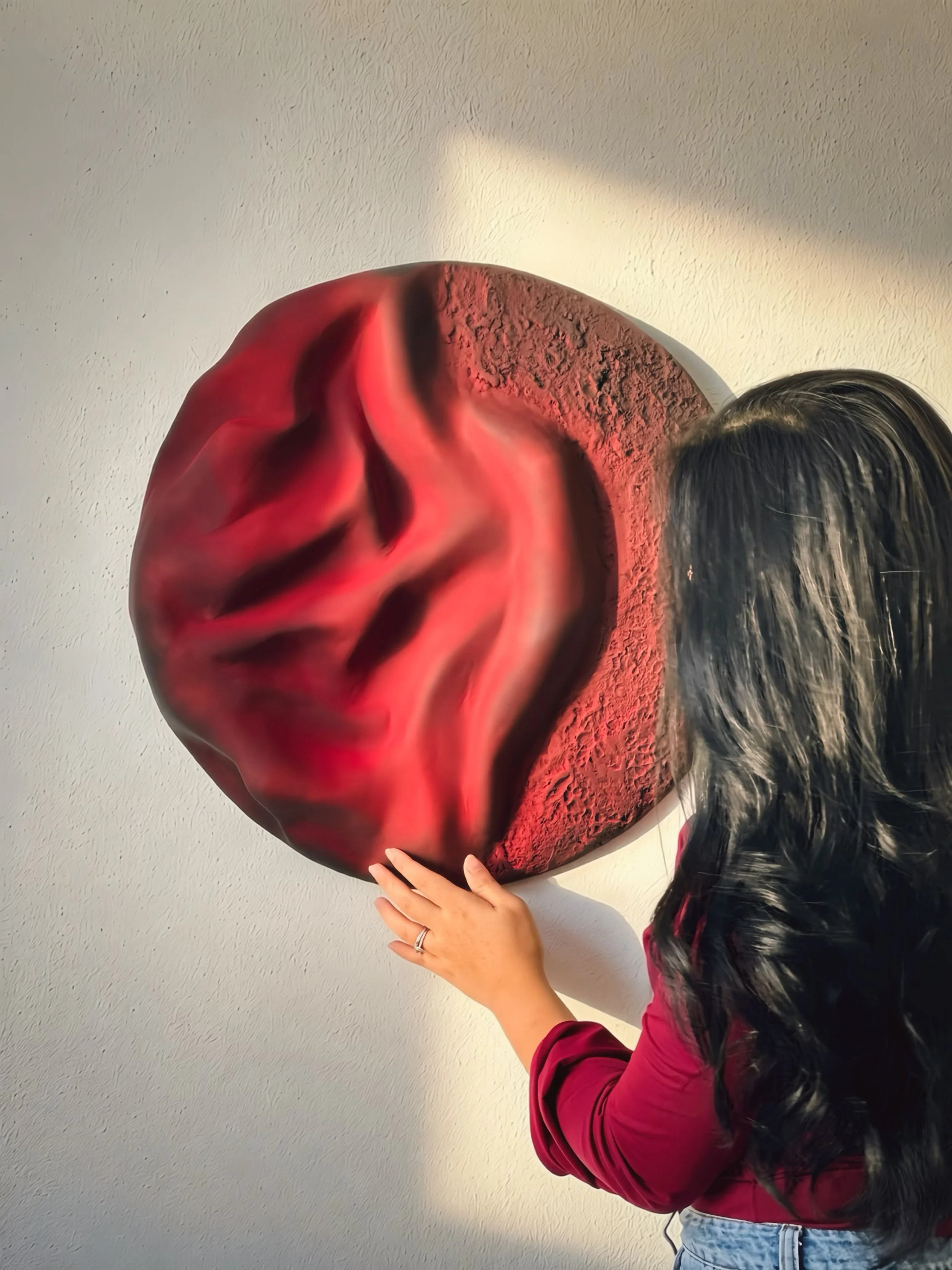Artist Shiela Ryan beside large circular textured wall artwork