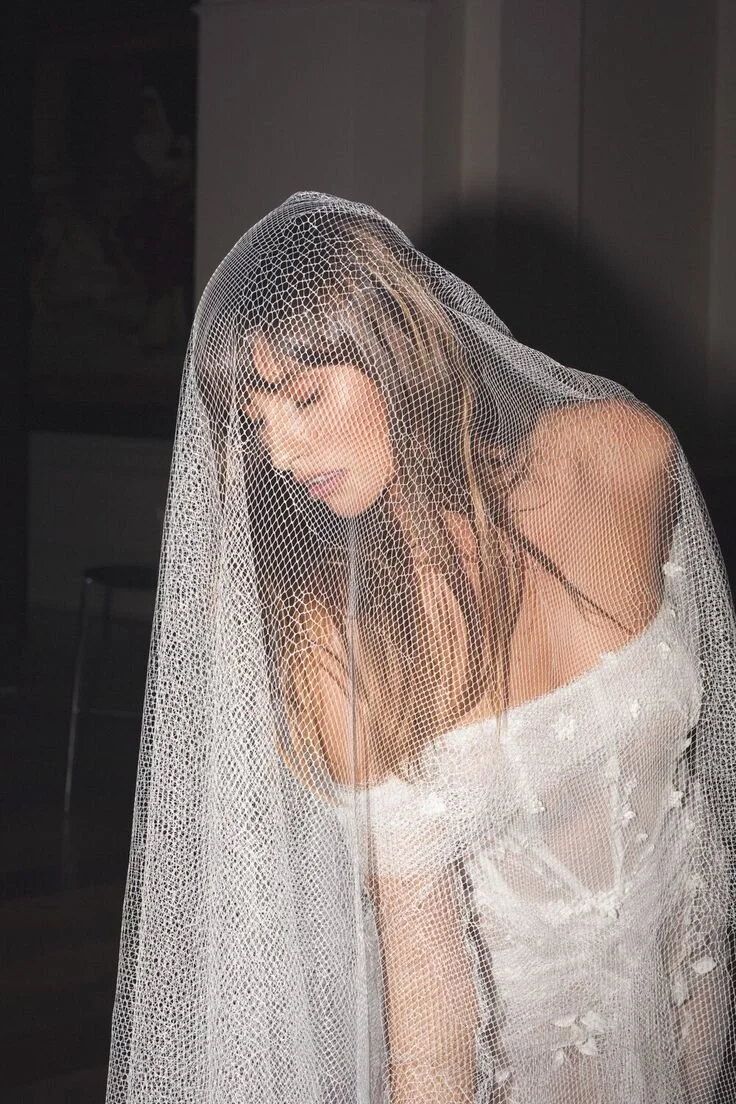 A woman in a wedding dress with lace details under a sheer veil