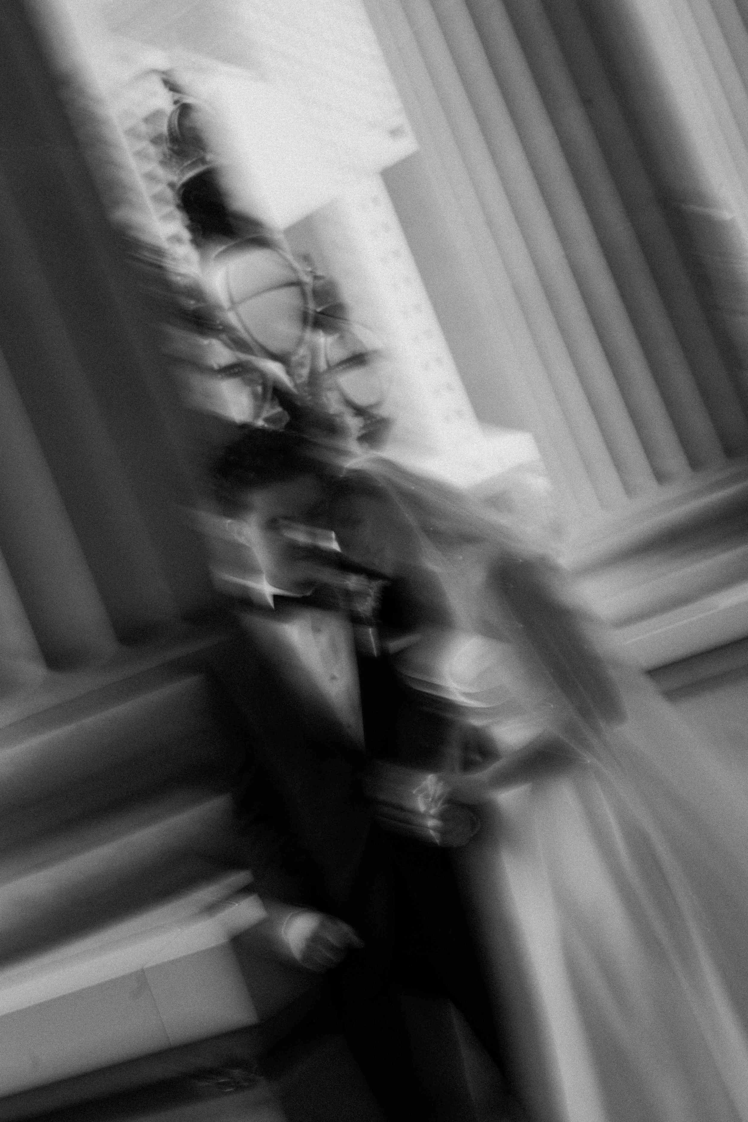 Blurry, editorial image of a couple in black and white photo, with roman pillars behind them