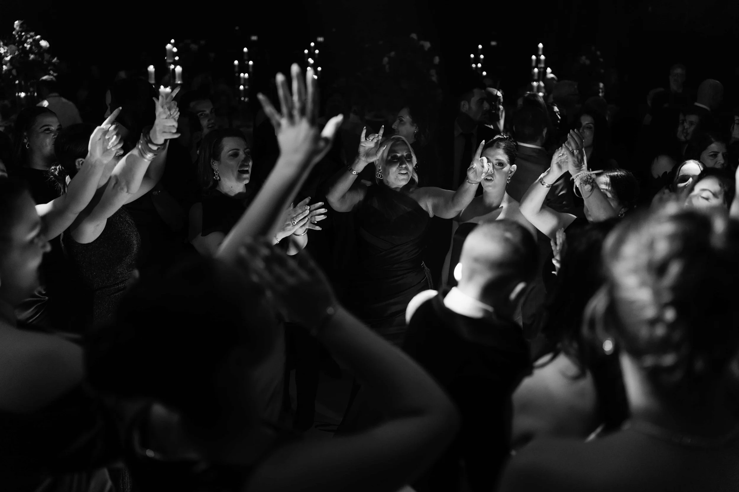 People dancing at a dark party or club with candlelit candles in the background.