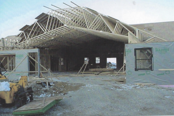 Construction site with a house under construction, framing in progress, and construction materials around.