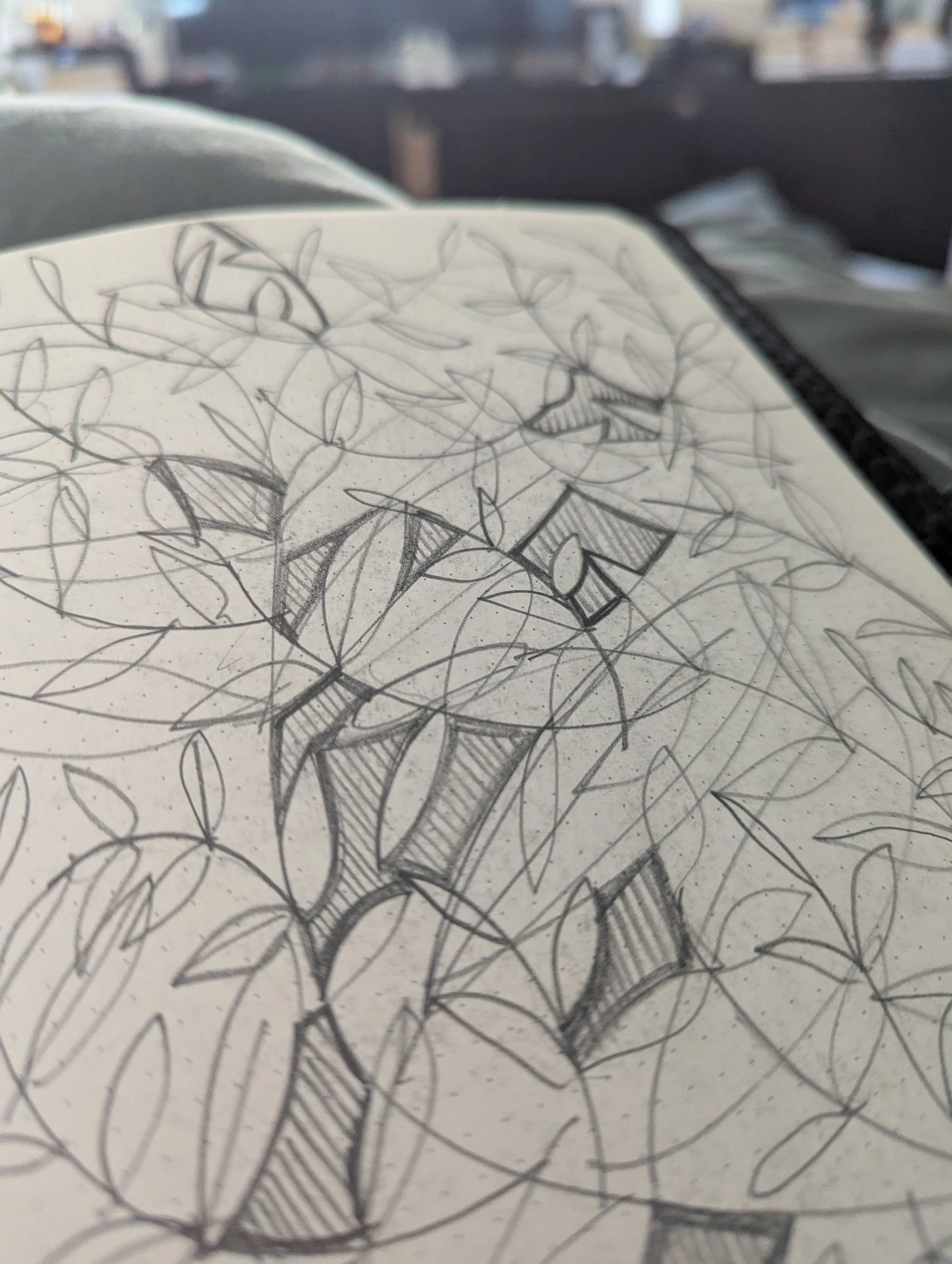 Close-up of a notebook page filled with a detailed pencil sketch of leaves, branches, and geometric shapes.