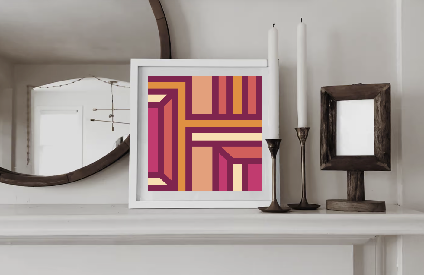 Contemporary geometric art print in pink, orange and burgundy tones  displayed in a white wood frame on a shelf in a contemporary interior.