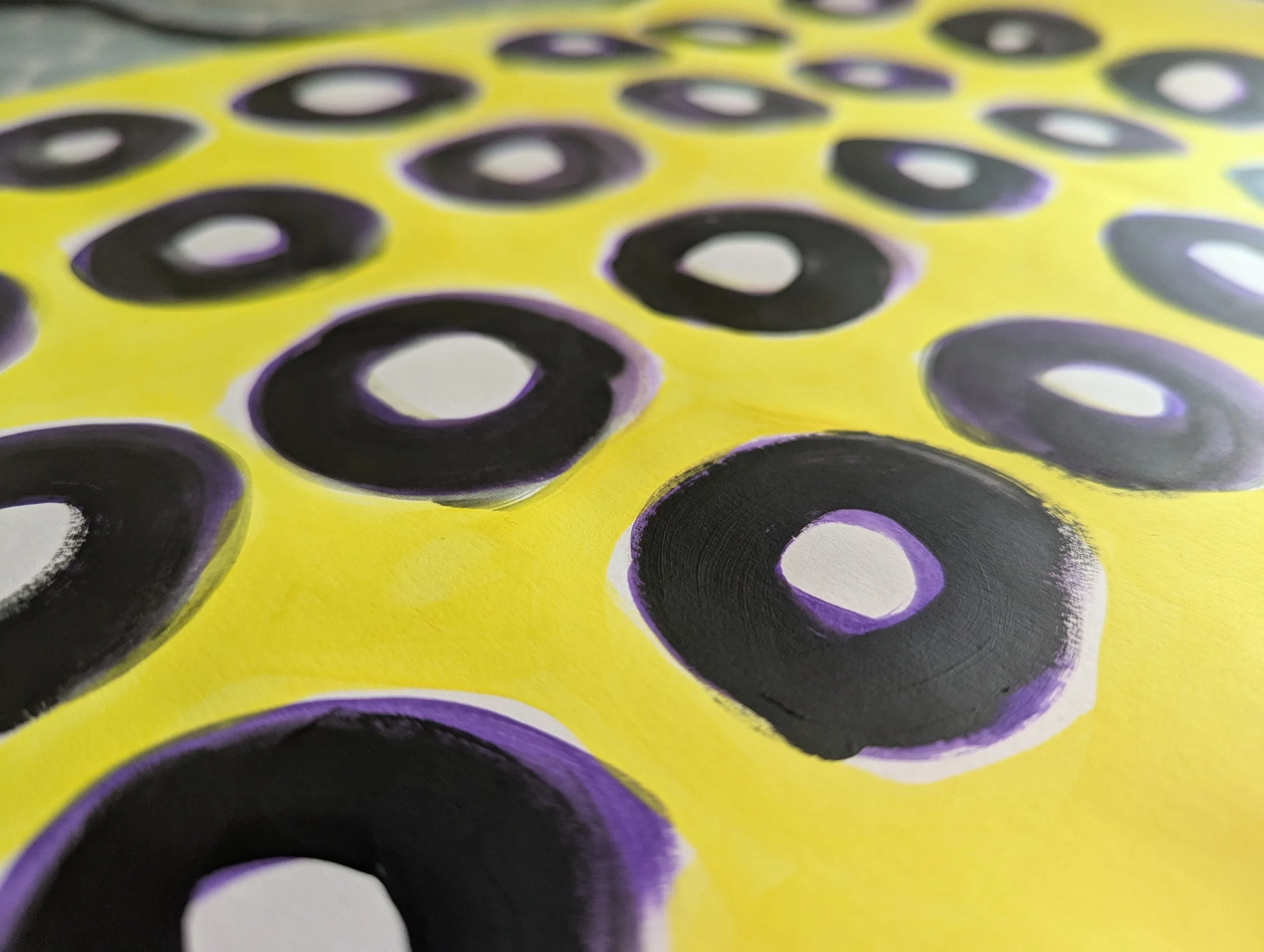 Close-up of a yellow surface with black and white eye-shaped patterns outlined in purple.