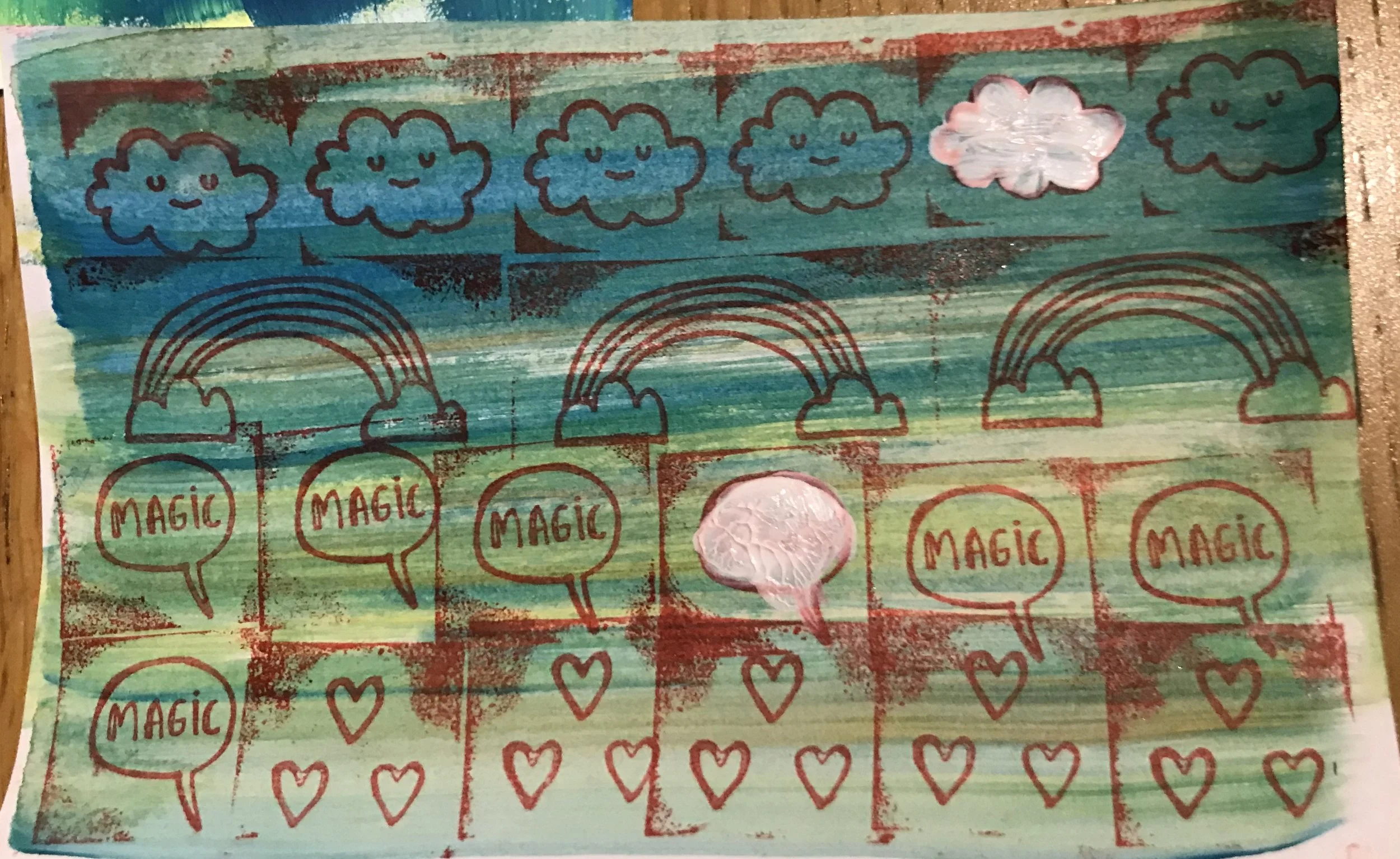 A colorful, handmade artwork with blue clouds, rainbows, and red speech bubbles with the word "MAGIC" written inside, created with markers and paint.