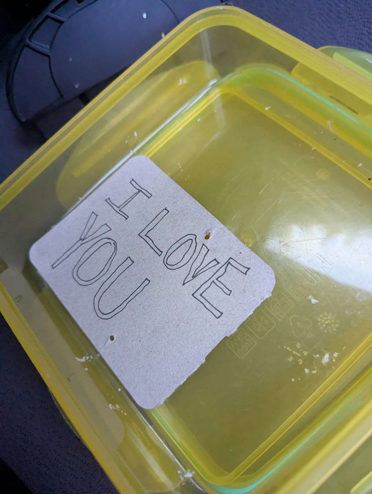 Close-up of a yellow plastic storage bin with a piece of paper inside that has the word 'HOME' written on it.