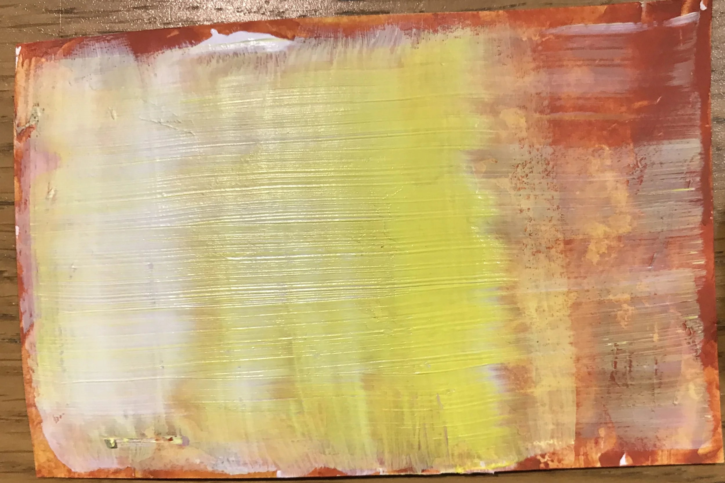 Abstract painting with horizontal strokes of yellow, white, and pink colors on a wooden surface with a reddish border.