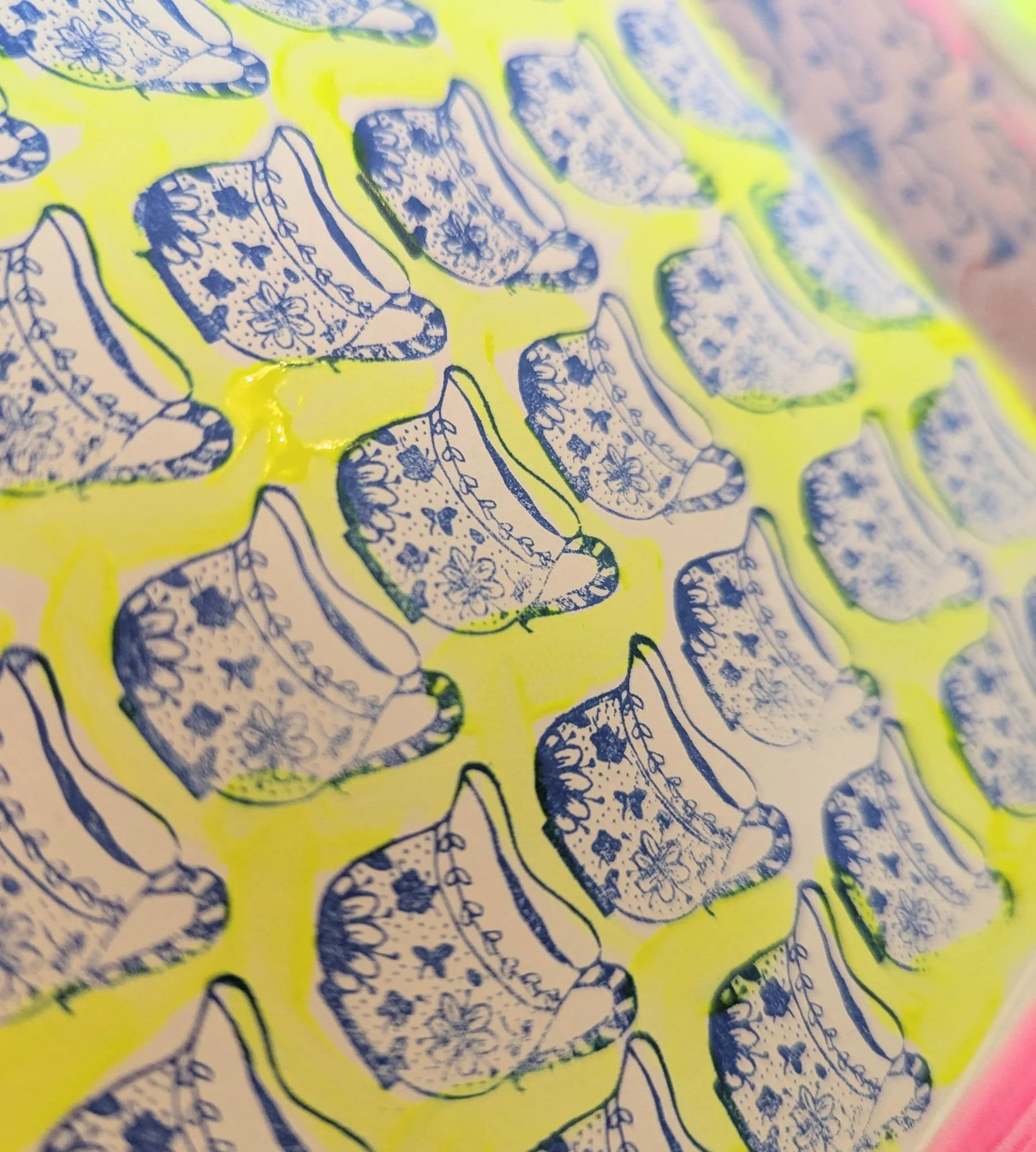 Close-up of a colorful abstract print with blue ink patterns resembling insects on a bright yellow background.