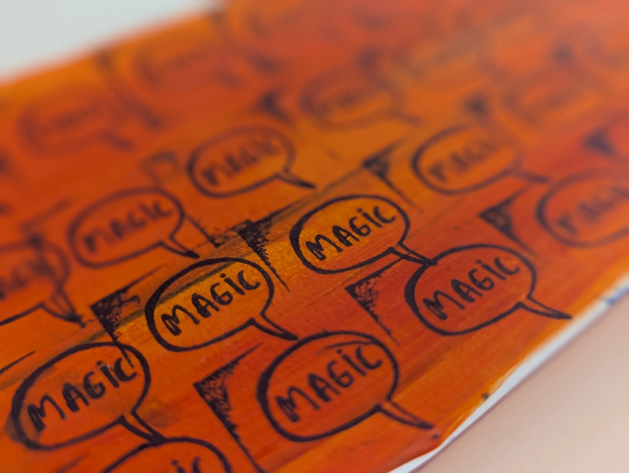 Close-up of a handwritten list on orange paper, with various items such as 'magic' and 'musical' written inside speech bubbles.