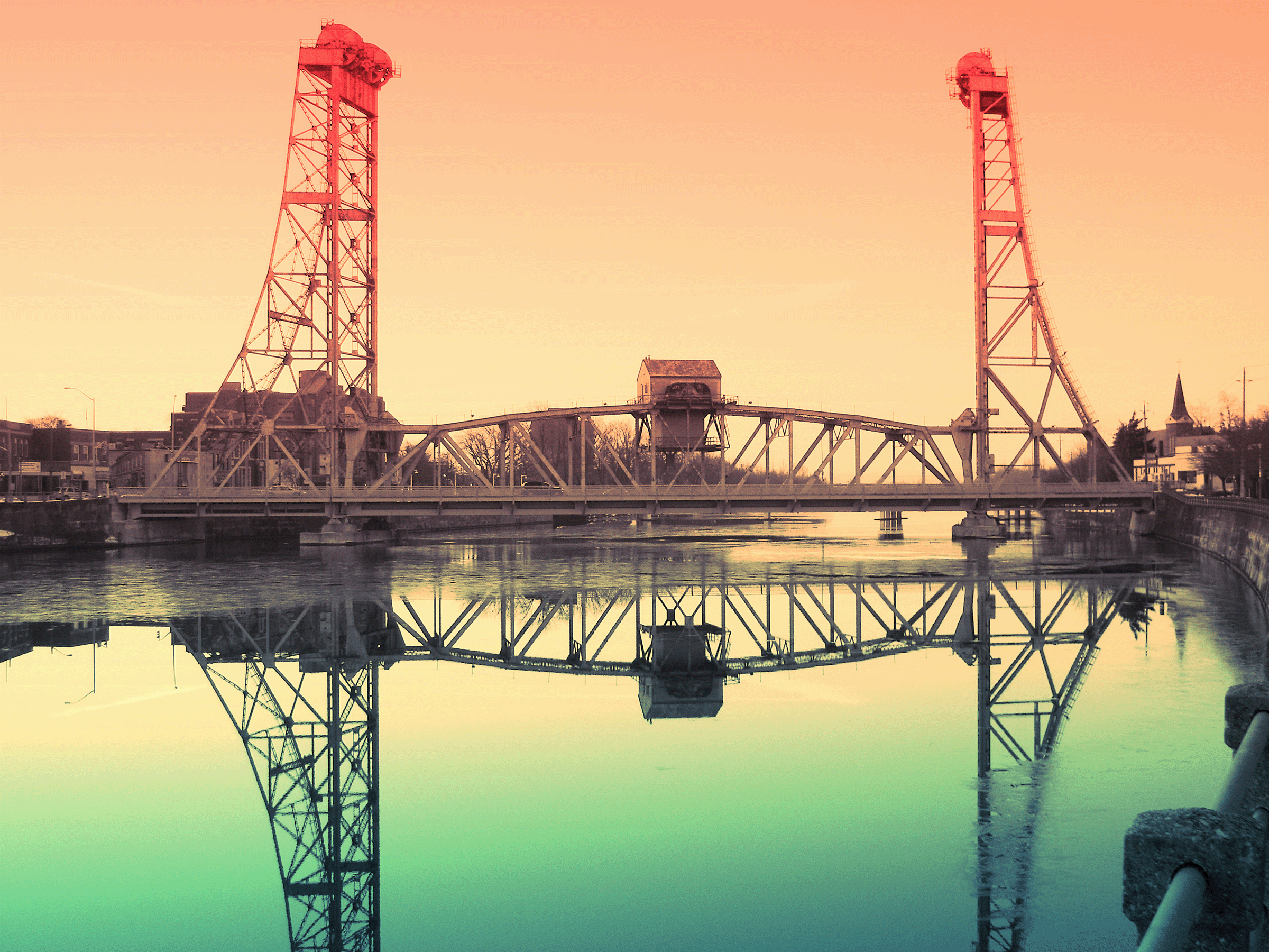 Bridge 13 in downtown Welland, reflected in a calm body of water during sunset with a pastel-colored sky.