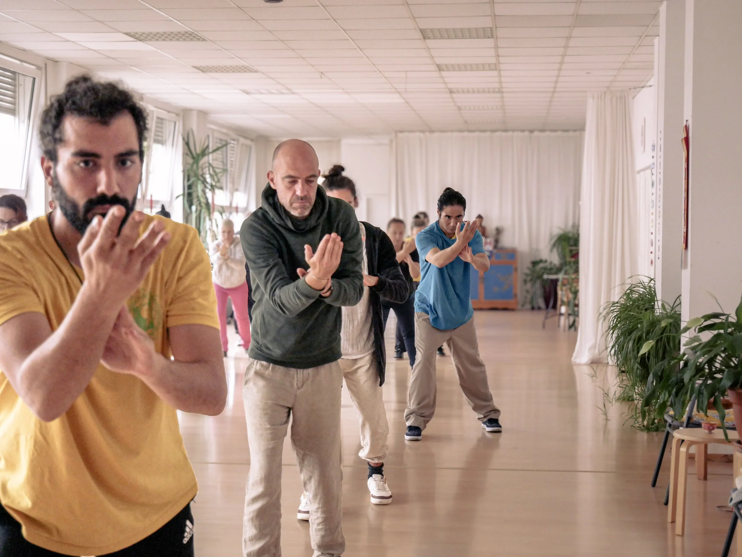 Menschen in einem Raum, die Taijiquan, Qigong, Taiji auf einem Kurs oder Workshop machen.