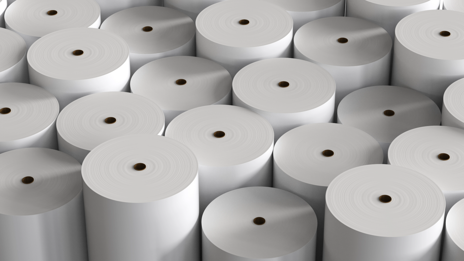 Multiple white rolls of paper stacked together in a warehouse or factory setting.