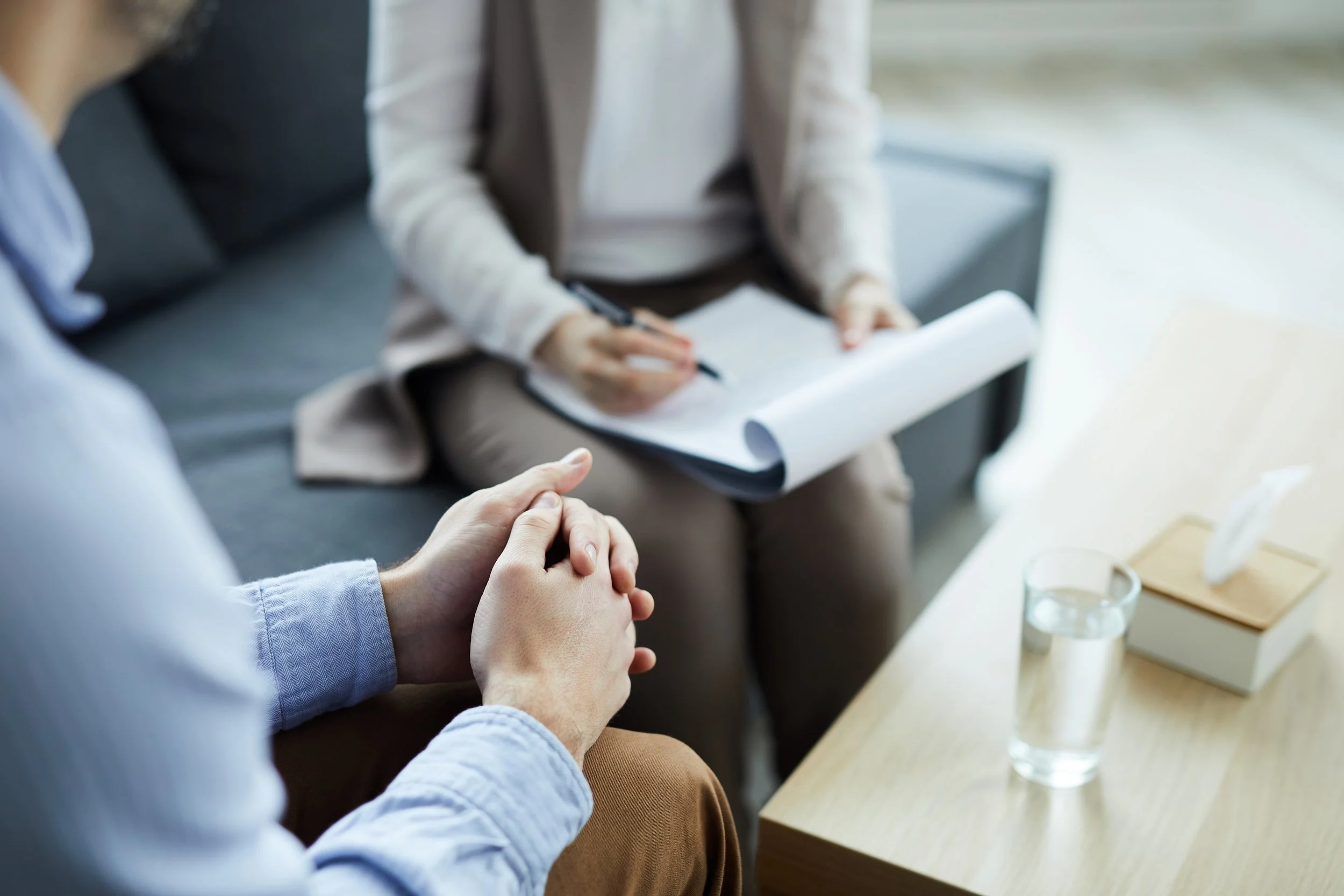 Man talking with therapist during counseling session while therapist takes notes