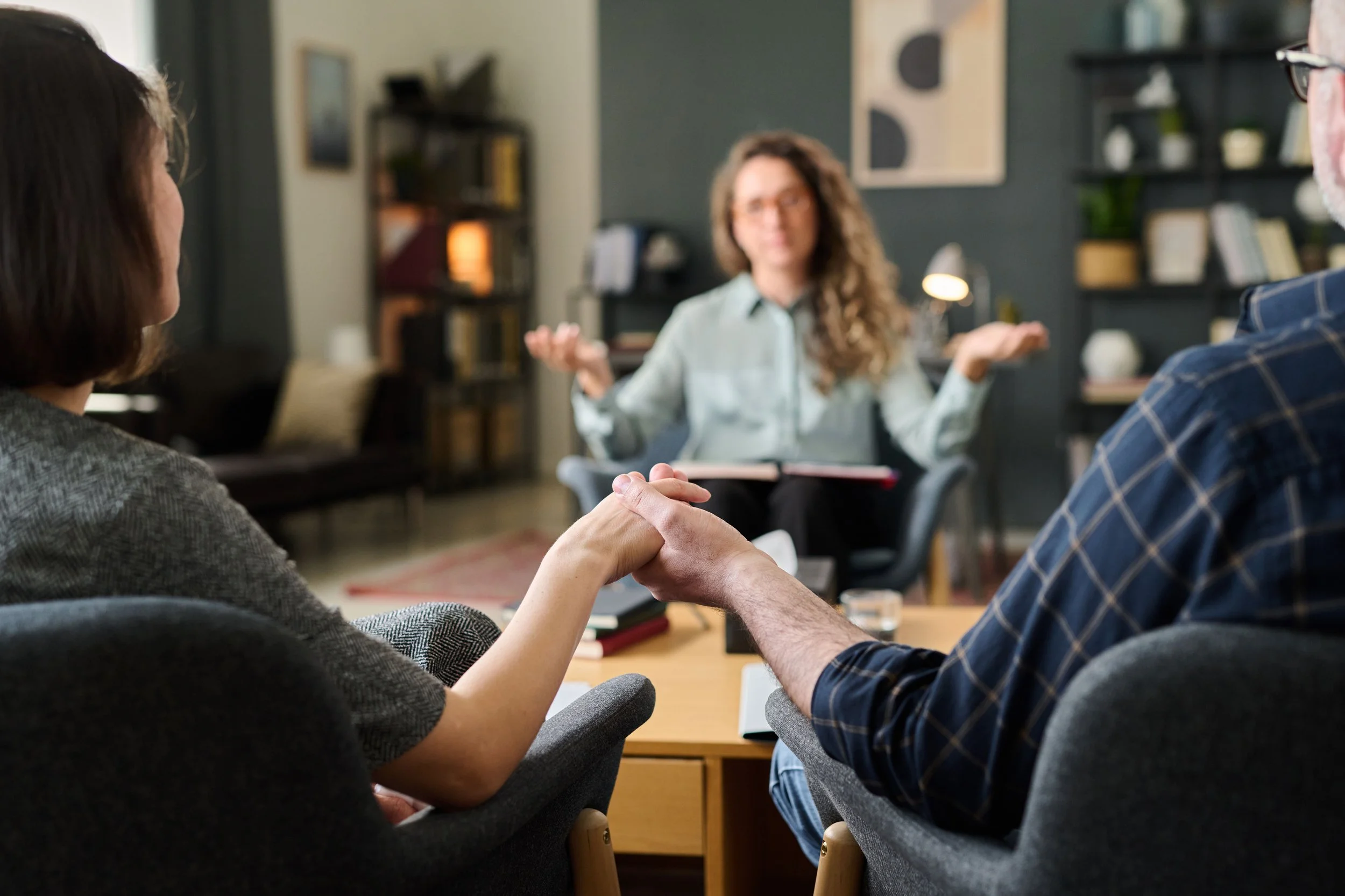Therapist talking to a couple who is holding hands
