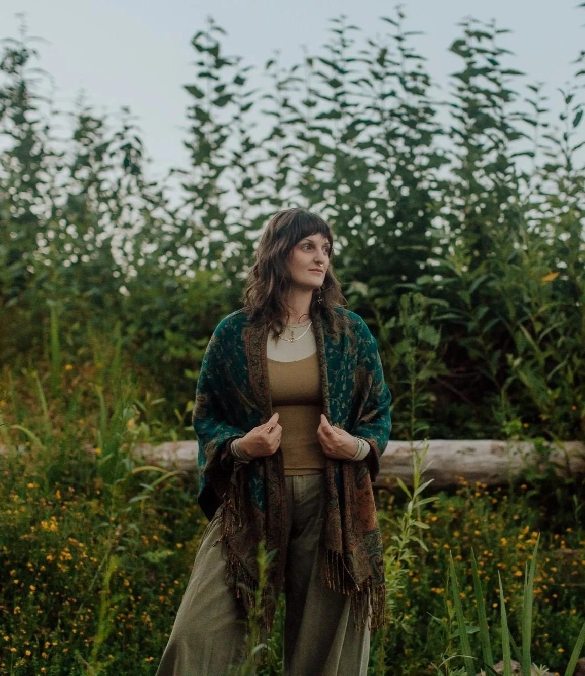 Emily Rose Meredith smiling in a paisley shawl beside a tree trunk near the water, hypnotherapist in Portland, Oregon