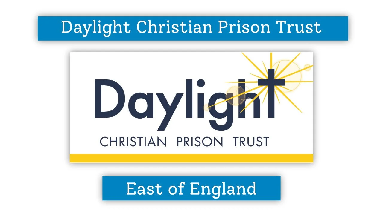 A logo for Daylight Christian Prison Trust, East of England. The logo features the word 'Daylight' with a cross integrated into the letter 't' and rays of light emanating from the cross, all set against a white background. The logo includes text on blue banners above and below, stating 'Daylight Christian Prison Trust' and 'East of England'.