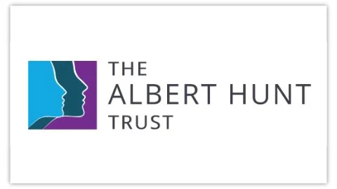 Logo of The Albert Hunt Trust showing two stylized blue and purple human profiles facing each other with the organisation's name.