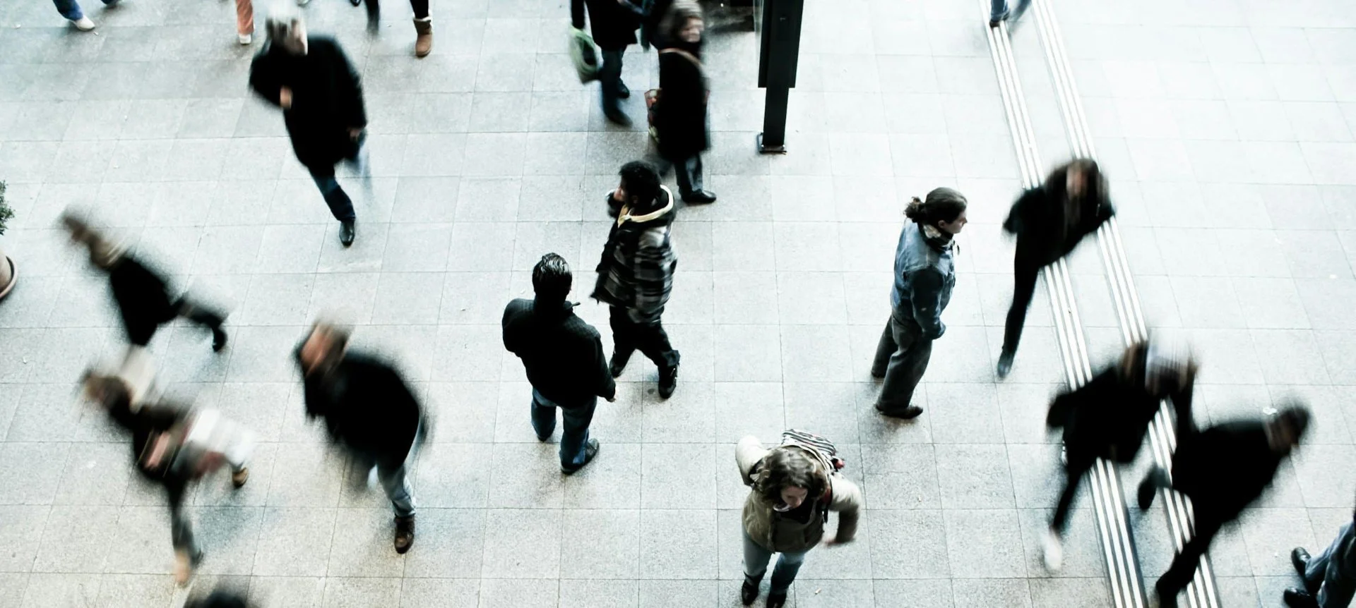 People walking in a busy indoor area, seen from above.