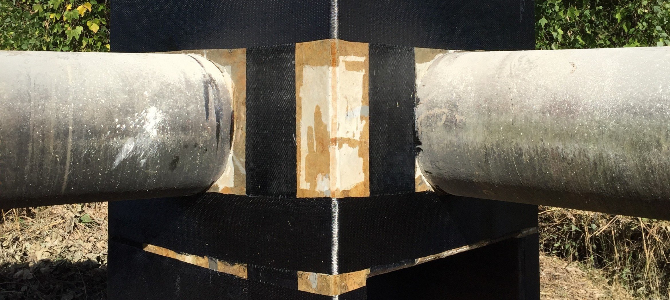 Close-up of two large metal pipes with carbon fiber strengthening