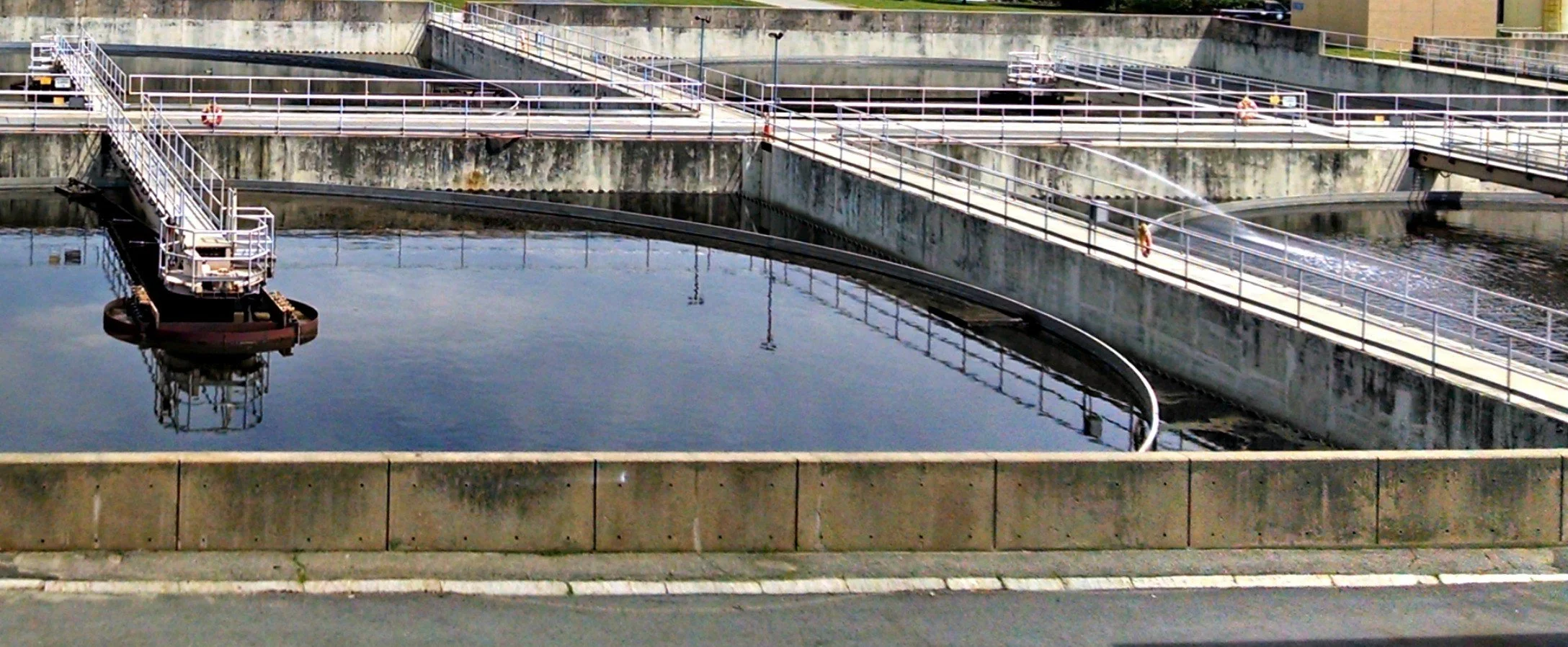 Water treatment facility with large tanks, walkways, and safety railings.