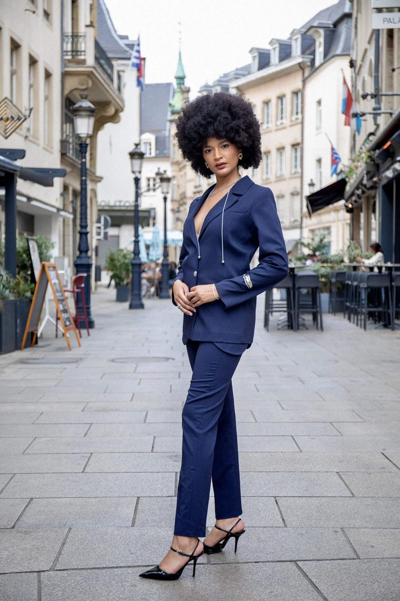 Full-length fashion editorial featuring model Ana in an elegant blue tailored suit by Francini_K, styled with Ennomerato jewelry. Photographed by Henri Da Cruz in the historic streets of Luxembourg City, highlighting contemporary tailoring, feminine 
