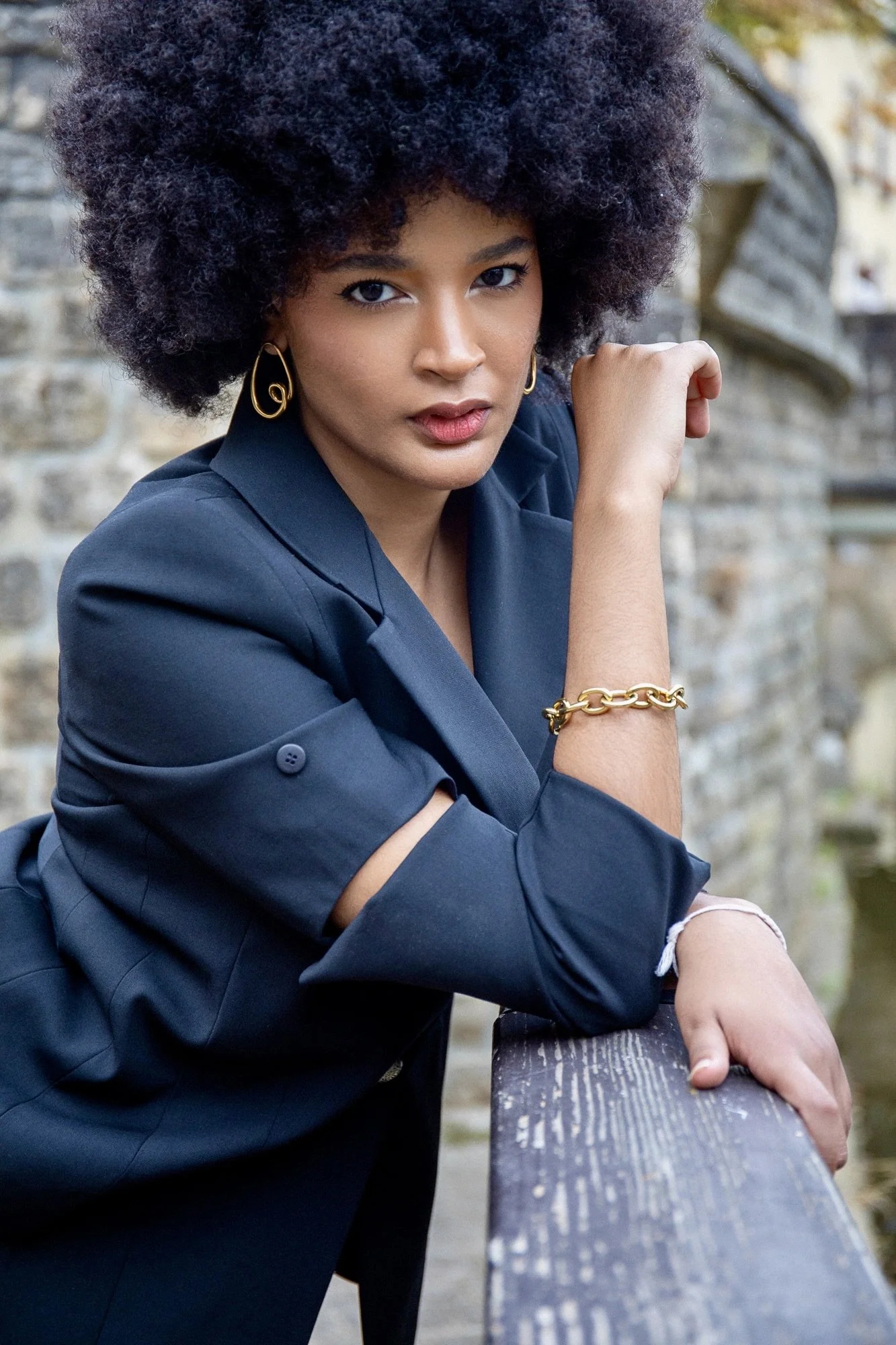 Fashion editorial portrait of model Ana wearing a navy blue tailored outfit by Francini_K, complemented by elegant gold jewelry from Ennomerato. Photographed by Henri Da Cruz in Luxembourg, highlighting refined accessories, natural beauty and contemp