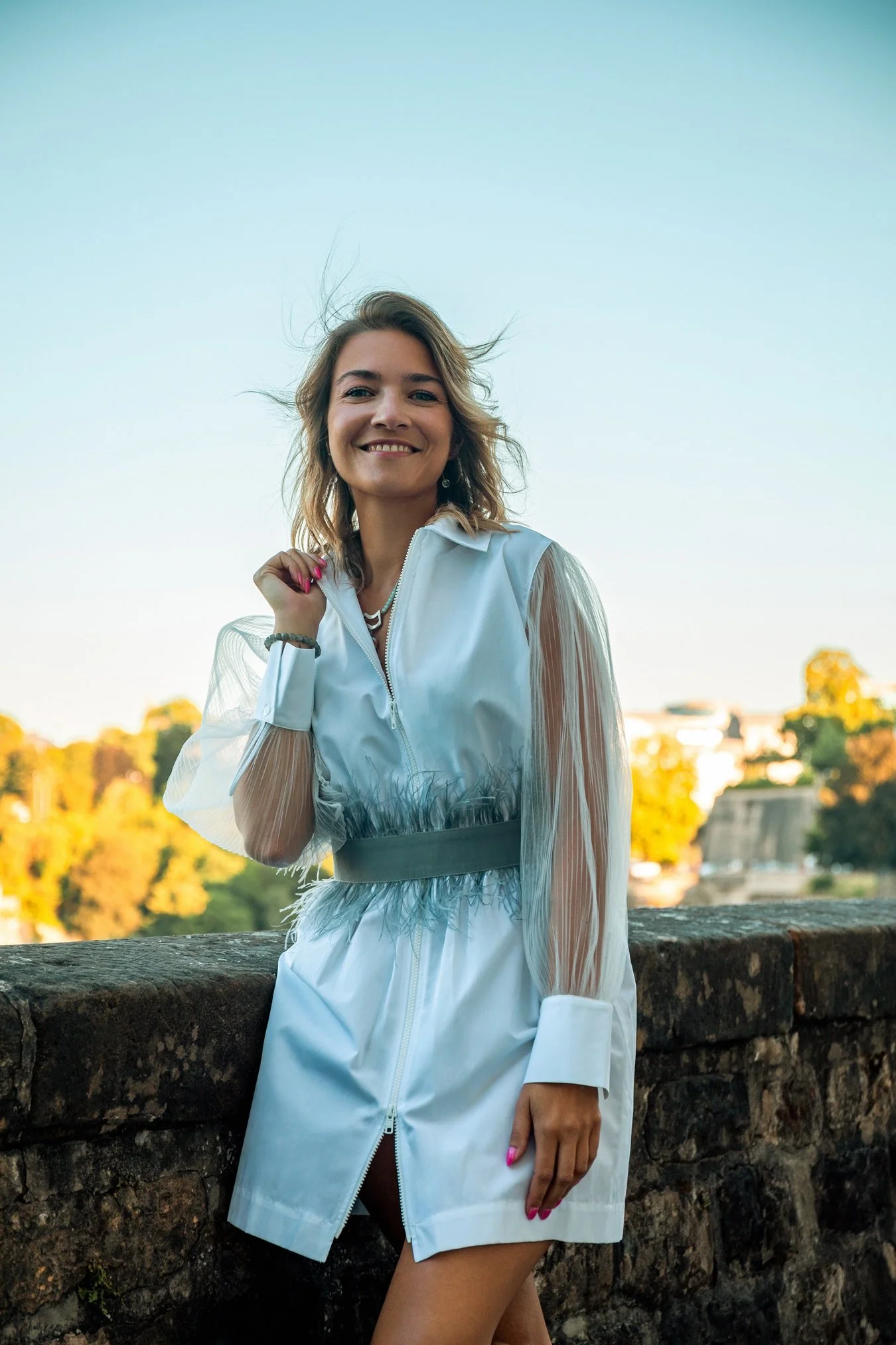 Fashion editorial photographed at golden hour in Luxembourg City, featuring a contemporary white look against the historic city backdrop, by Henri Da Cruz.