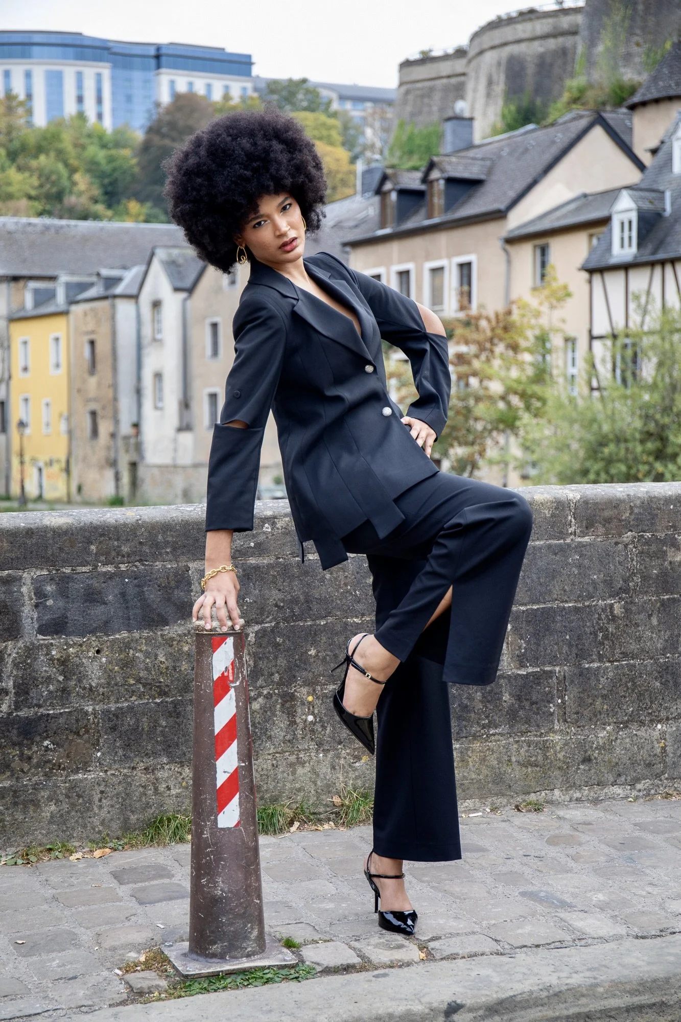 Full-body fashion editorial featuring model Ana in a sophisticated black tailored outfit by Francini_K, accessorized with Ennomerato jewelry. Dynamic urban fashion photography in Luxembourg by Henri Da Cruz, highlighting contemporary elegance, confid