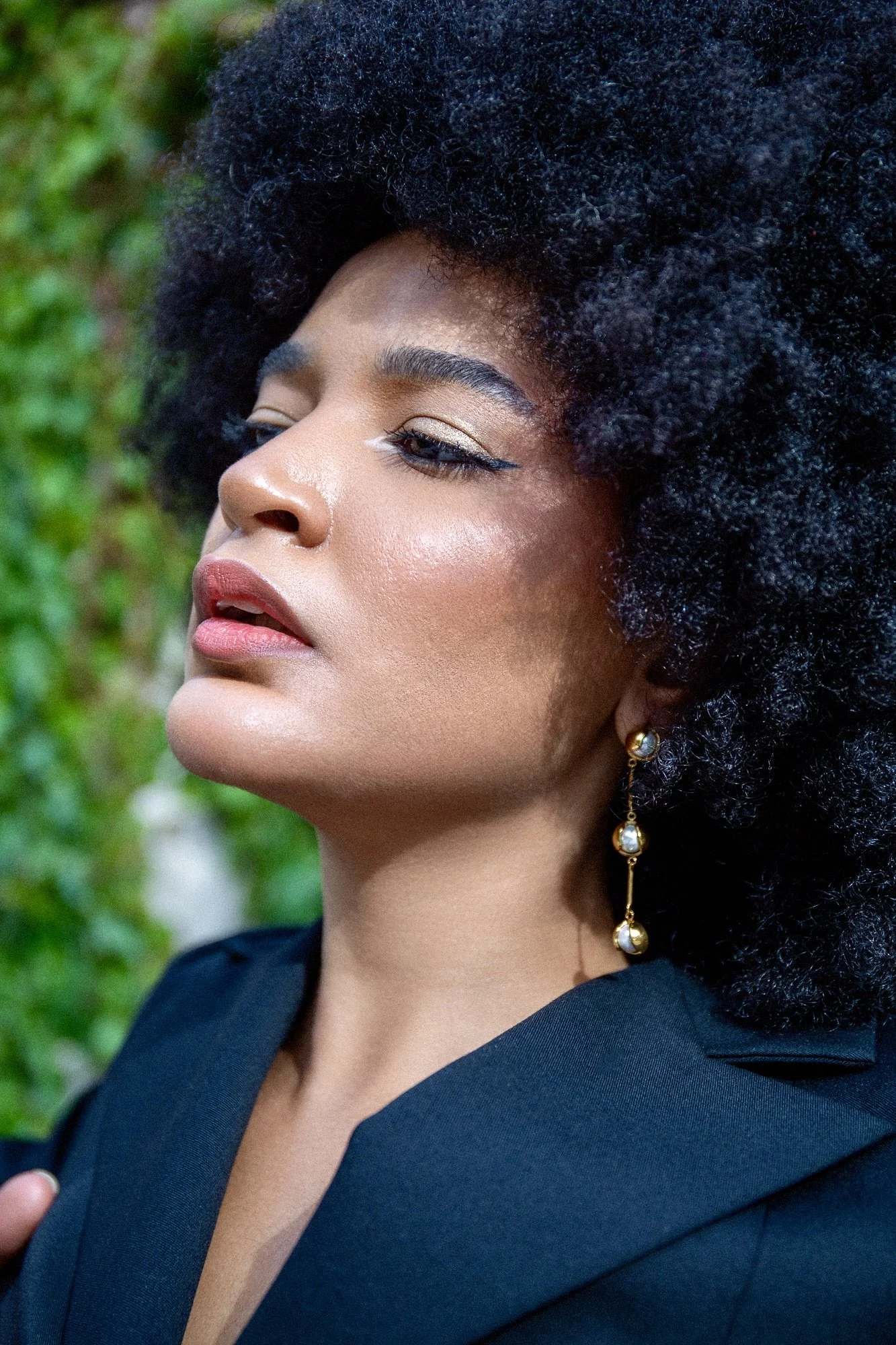 Close-up fashion and jewelry portrait of model Ana wearing elegant gold drop earrings by Ennomerato and a black tailored blazer by Francini_K. Editorial photography in Luxembourg by Henri Da Cruz.