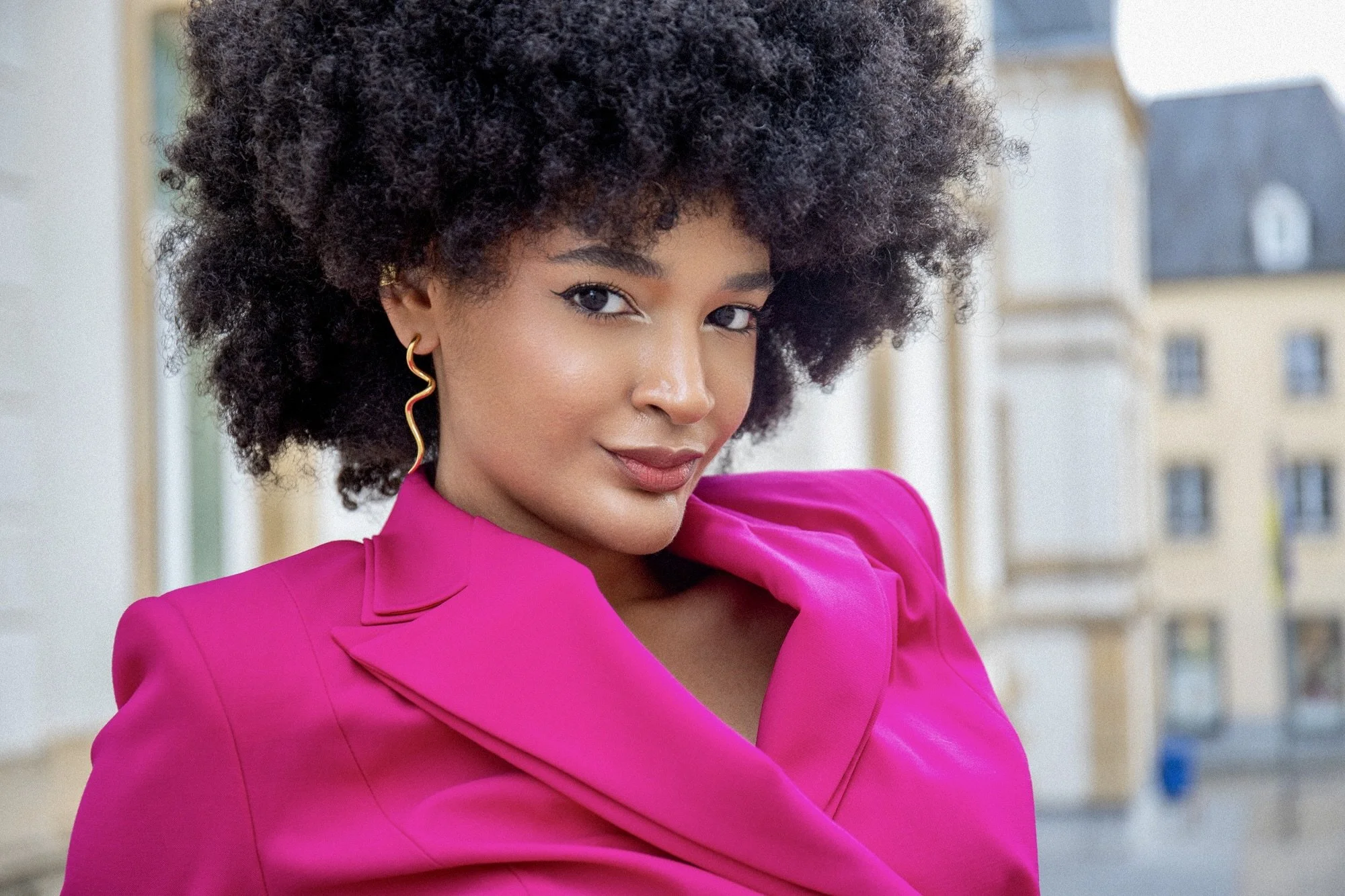 Contemporary fashion portrait of model Ana wearing a vibrant fuchsia tailored blazer by Francini_K, photographed by Henri Da Cruz in Luxembourg City. A confident expression, structured shoulders and elegant gold earrings highlight modern femininity a