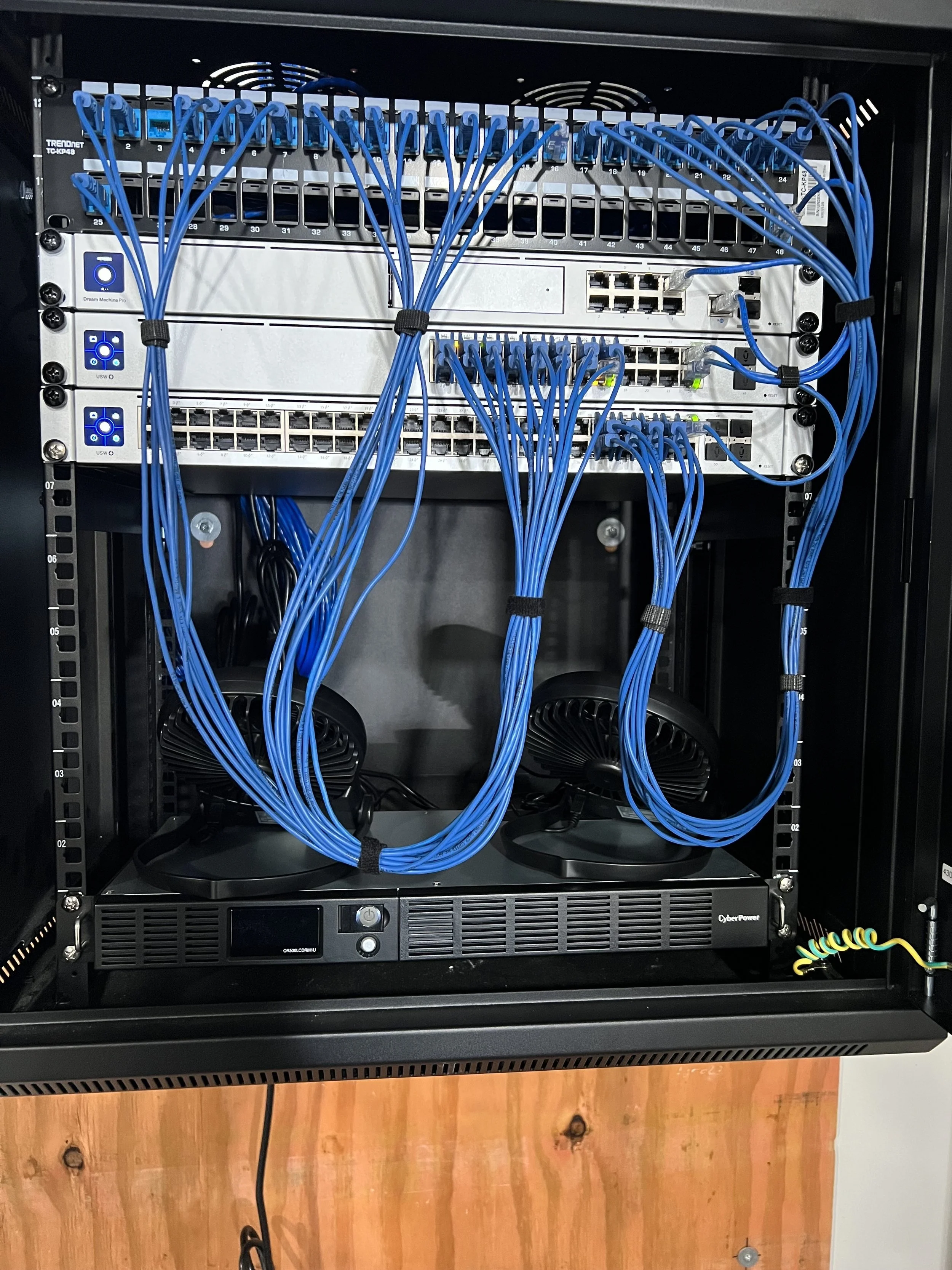 A server rack containing network switches and cables, with blue Ethernet cables connected to various ports, some bundled with cable ties.