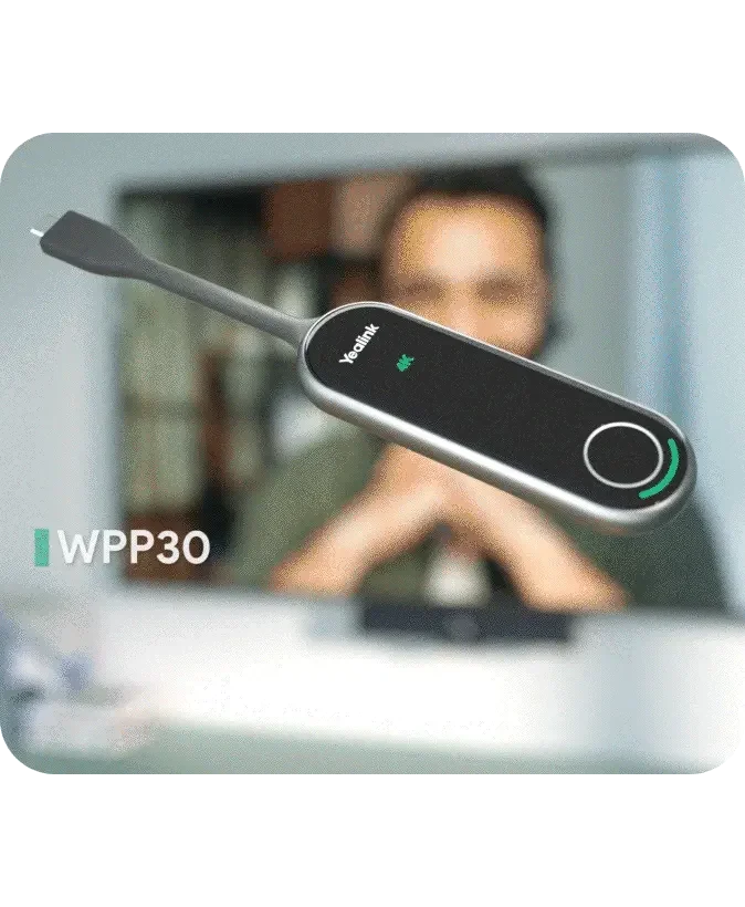 Close-up of a Yealink WPP30 wireless presentation device in front of a person blurred in the background, in an indoor setting.
