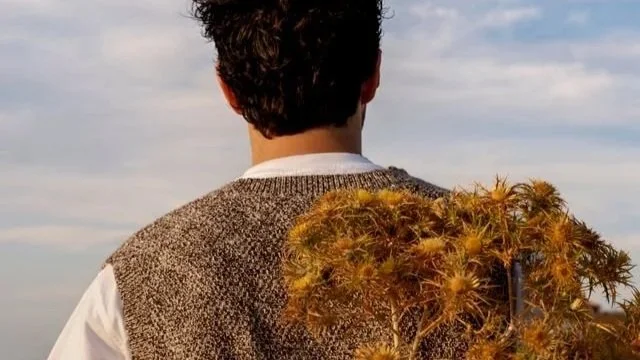A man holding a bundle of flowers behind his back
