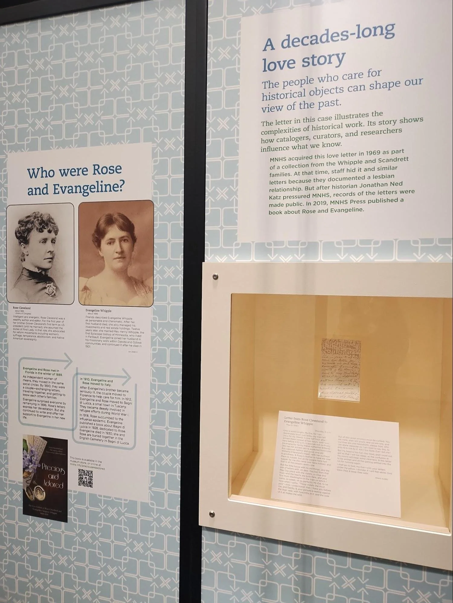 A museum exhibit with an informational panel titled "A Decades-Long Love Story"  including photographs of two women and a handwritten letter in a glass case.