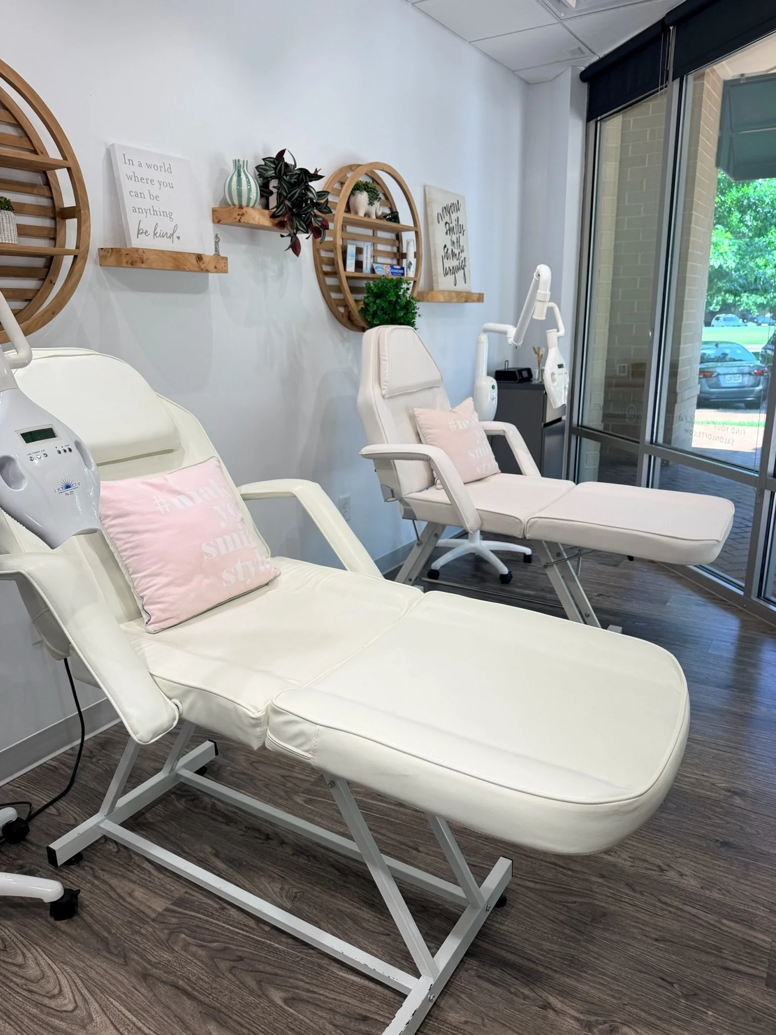 An overview of the teeth whitening session room with two dental chairs, both with light pink pillows reading "#MakeYouSmileStyle".