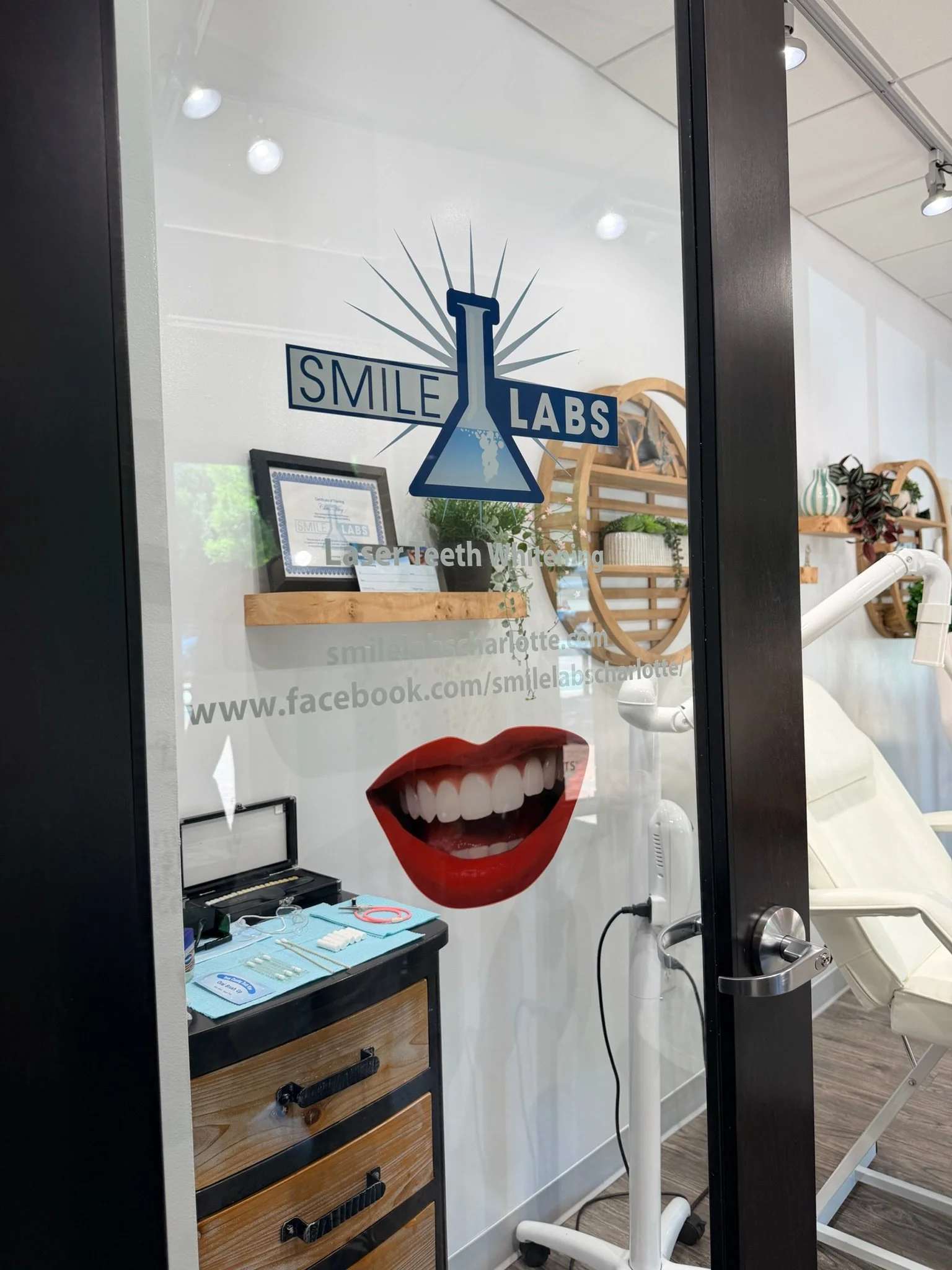 A dental office window with the Smile Labs logo, a smiling mouth with white teeth, a beaker, and the text 'Laser Teeth Whitening.'