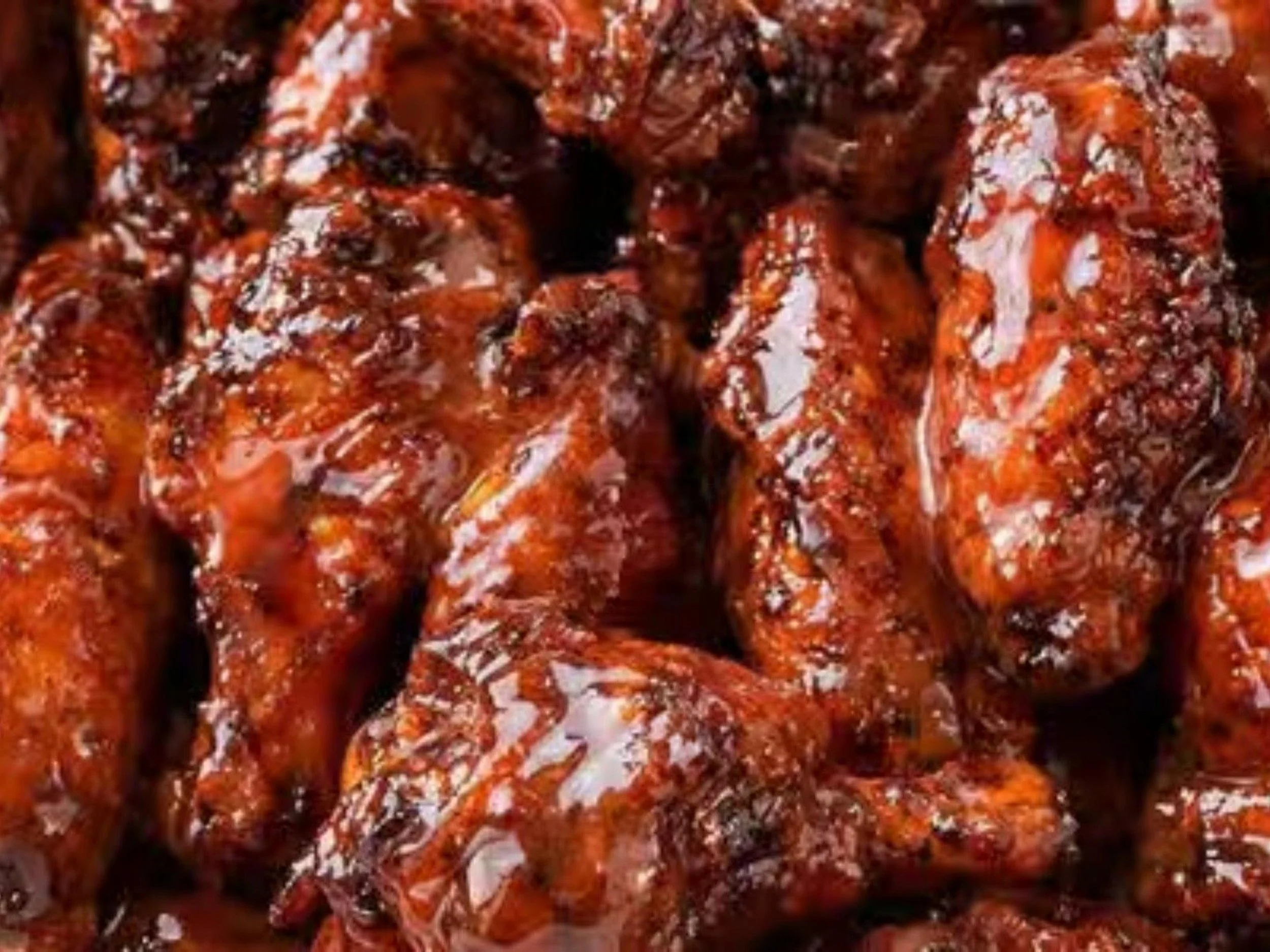Close-up of cooked and seasoned shrimp coated in a thick red sauce.