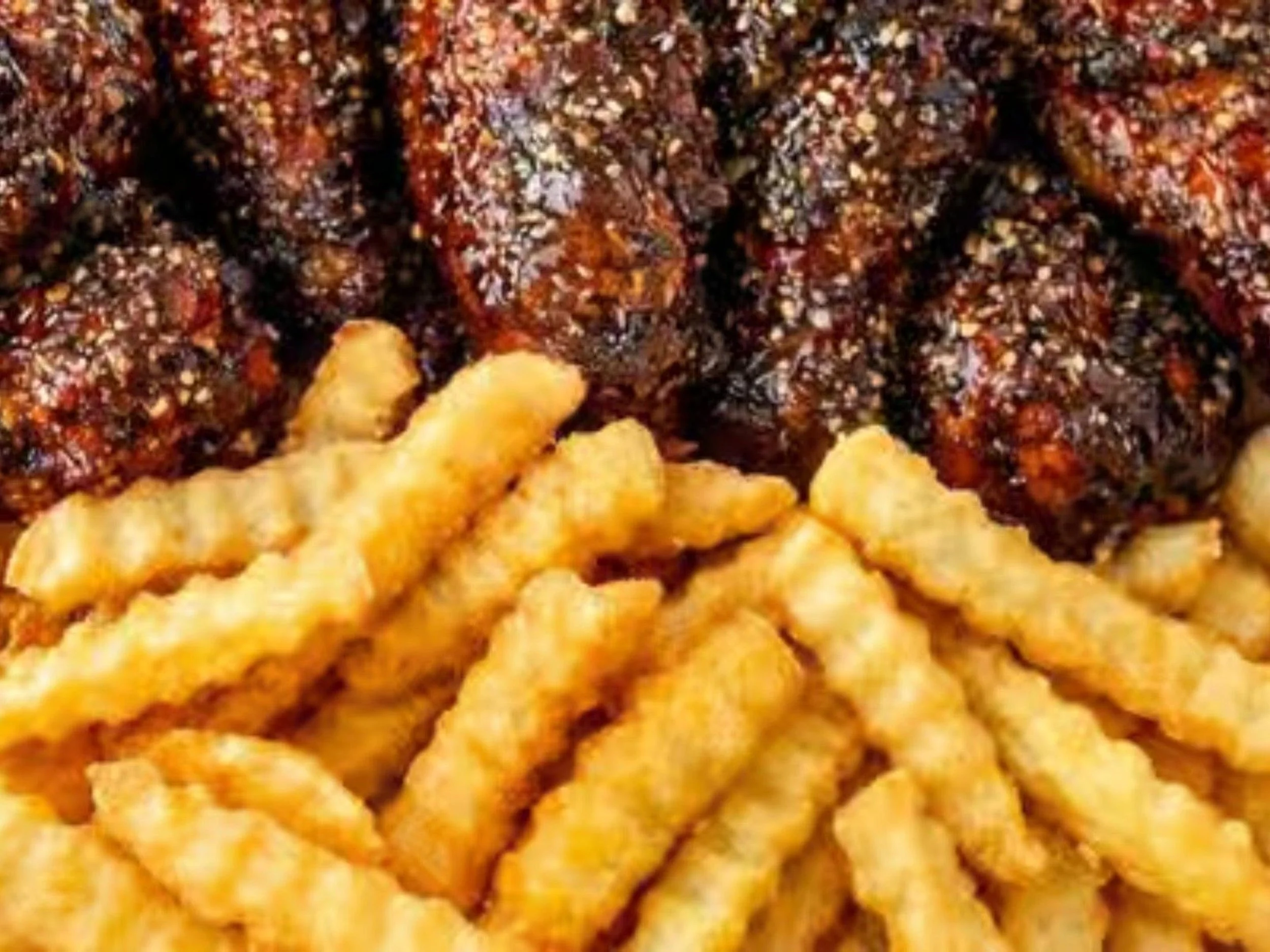 Close-up image of fried chicken pieces served with crinkle-cut French fries.