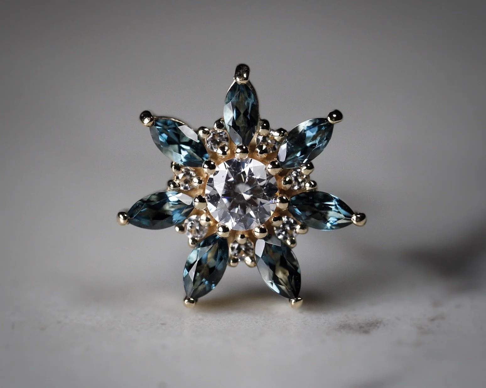 Broche decorativa con piedras brillantes en forma de estrella, con piedras azules y transparentes.