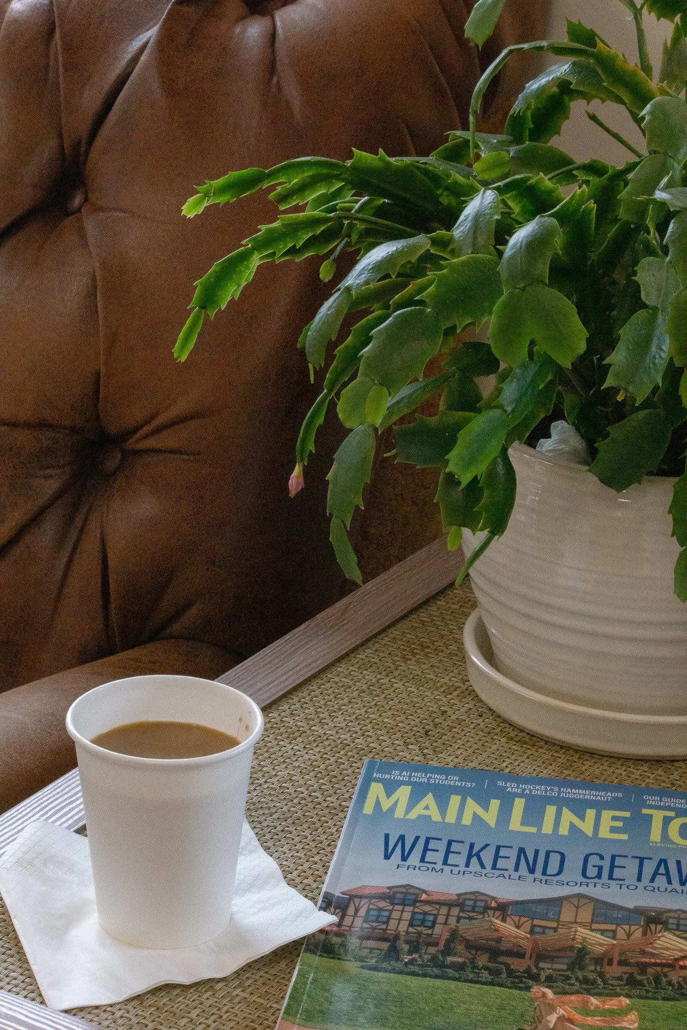 Coffee on a side table in lounge area at Prestige Salon in Wayne, PA, and a Main Line Today Newspaper