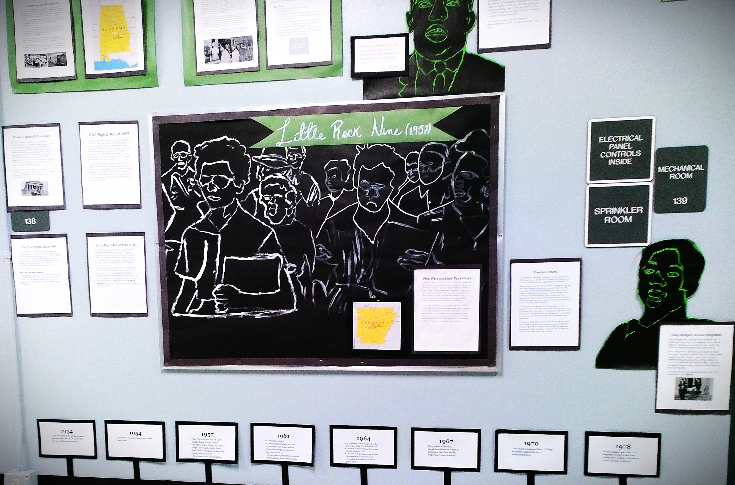 A museum display about the Little Rock Nine, featuring a black and white outline illustration of nine African American students protesting racial segregation in schools, surrounded by informational plaques and signs about civil rights history.