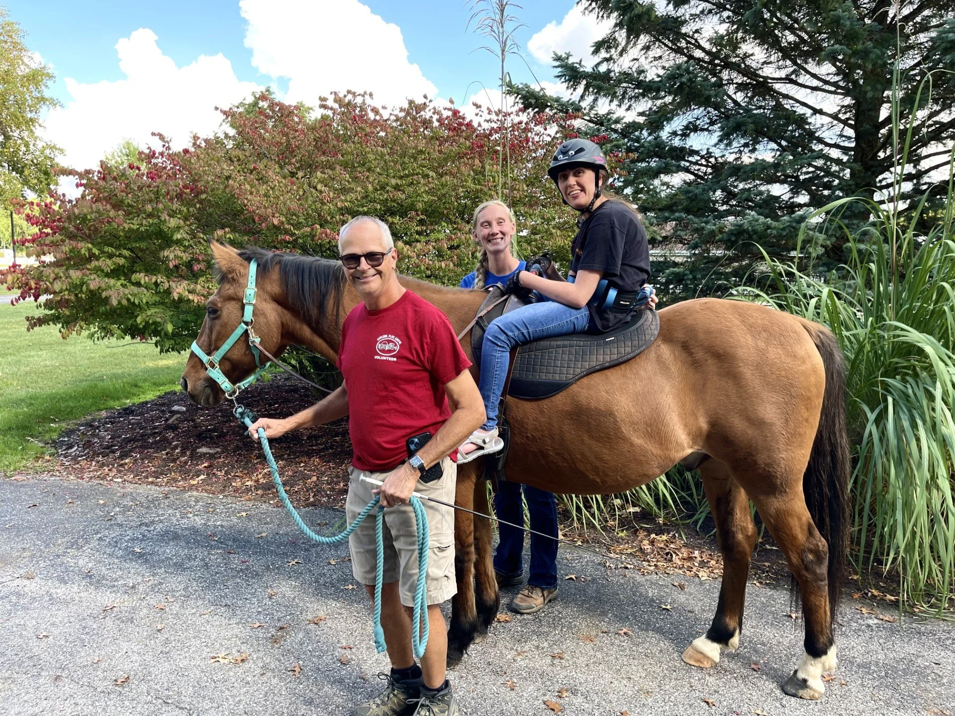A Camp Red Cedar therapeutic horseback riding participant (seated on the horse) and her parents at Camp Red Cedar in Fort Wayne, Indiana.