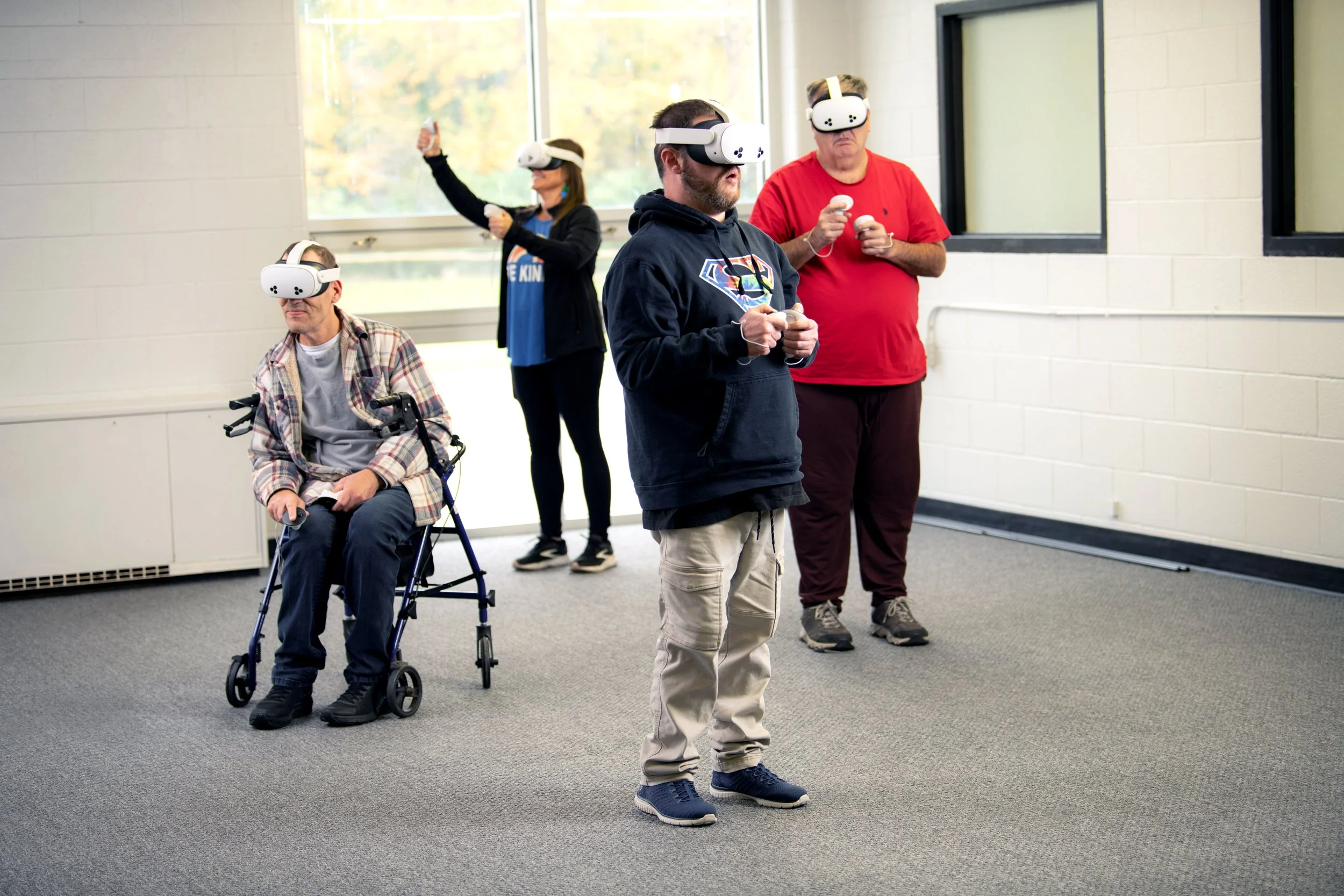 Four residents of Enact Residential Services stand in a room engaging in a virtual reality activity.