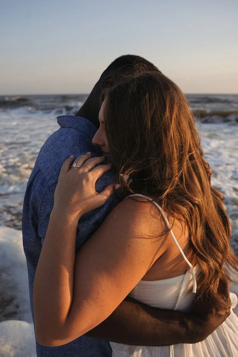 A couple hugging on the beach at sunset.