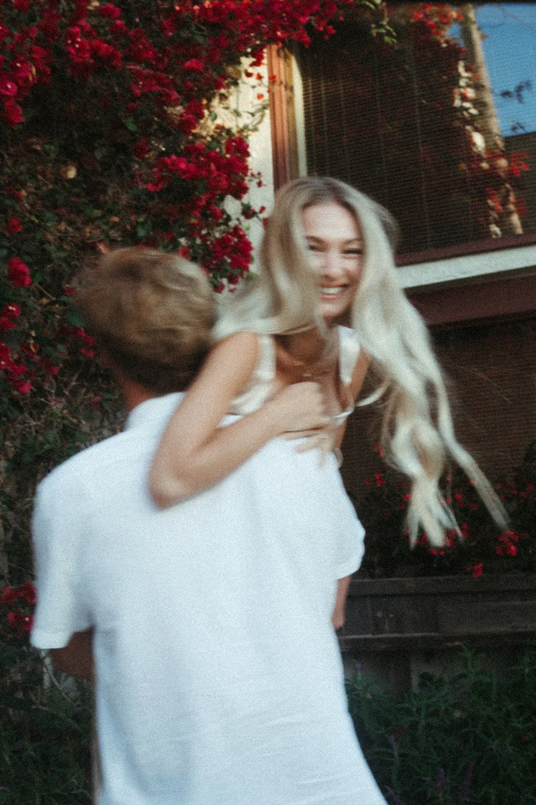 A man carries his laughing fiance in all white over his shoulder during their engagement session at Carmel by the Sea