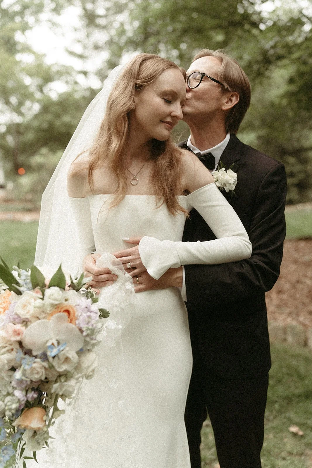 An elegantly dressed wedding couple embraces in a kiss on their wedding day in Charlotte, North Carolina