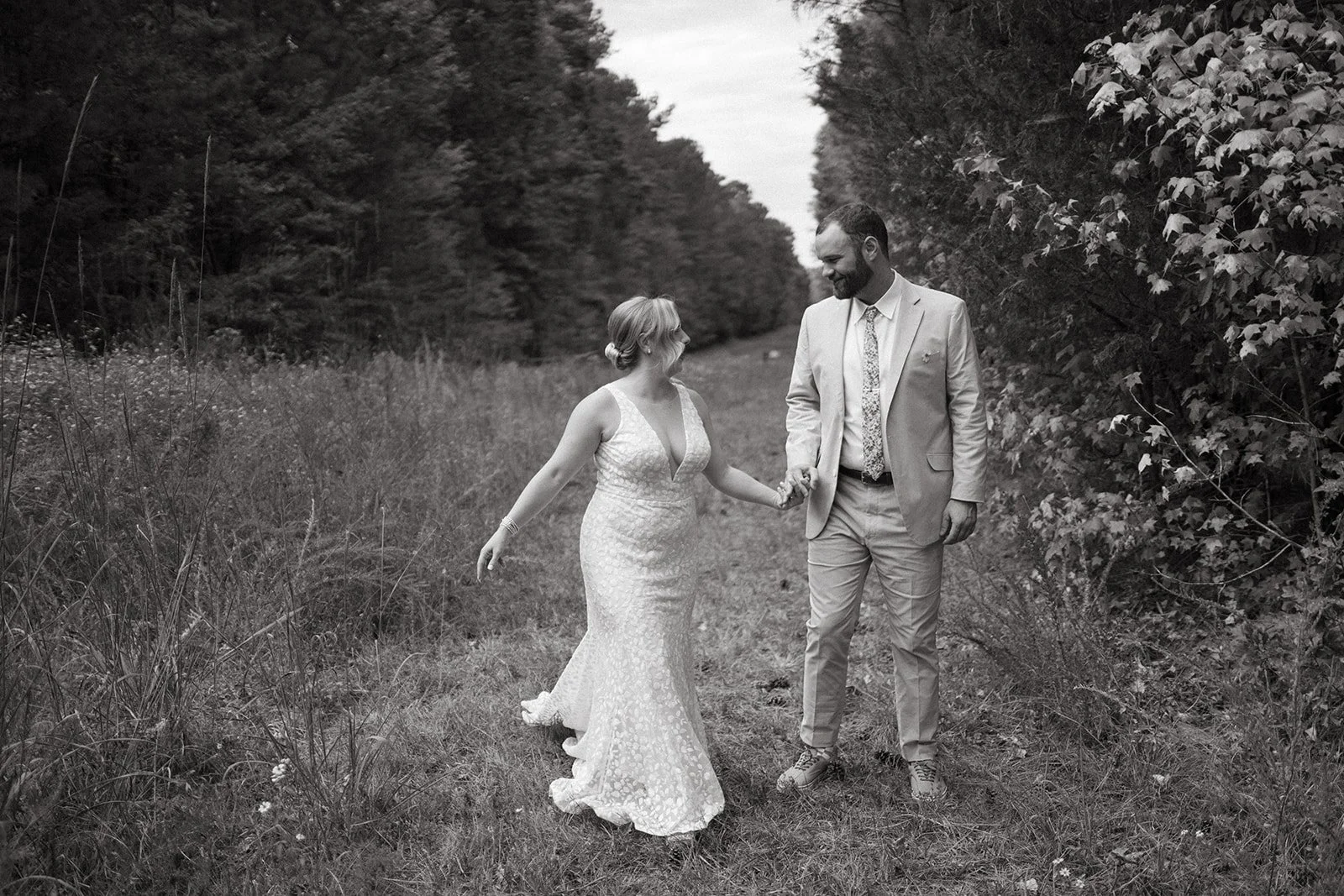 This is an image of a wedding couple walking down a path on the Shakori Hills festival grounds in North Carolina.